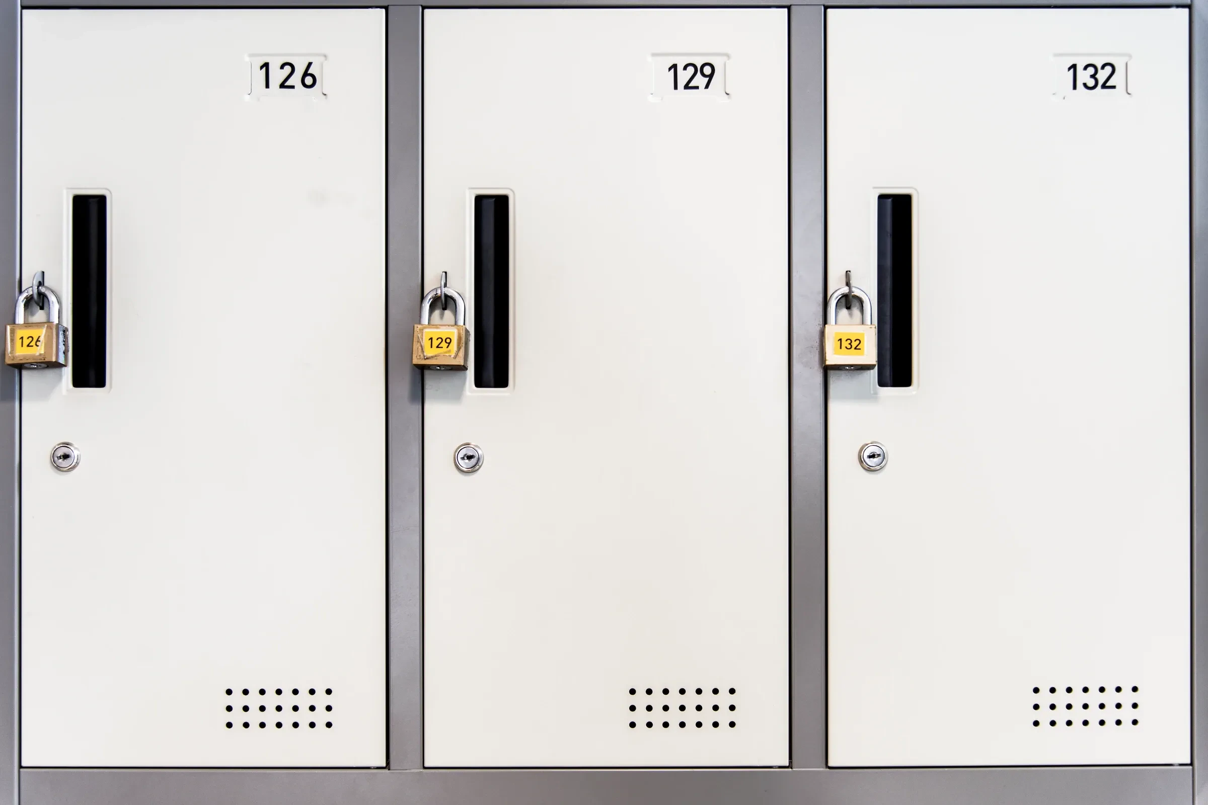 A row of white lockers with padlocks