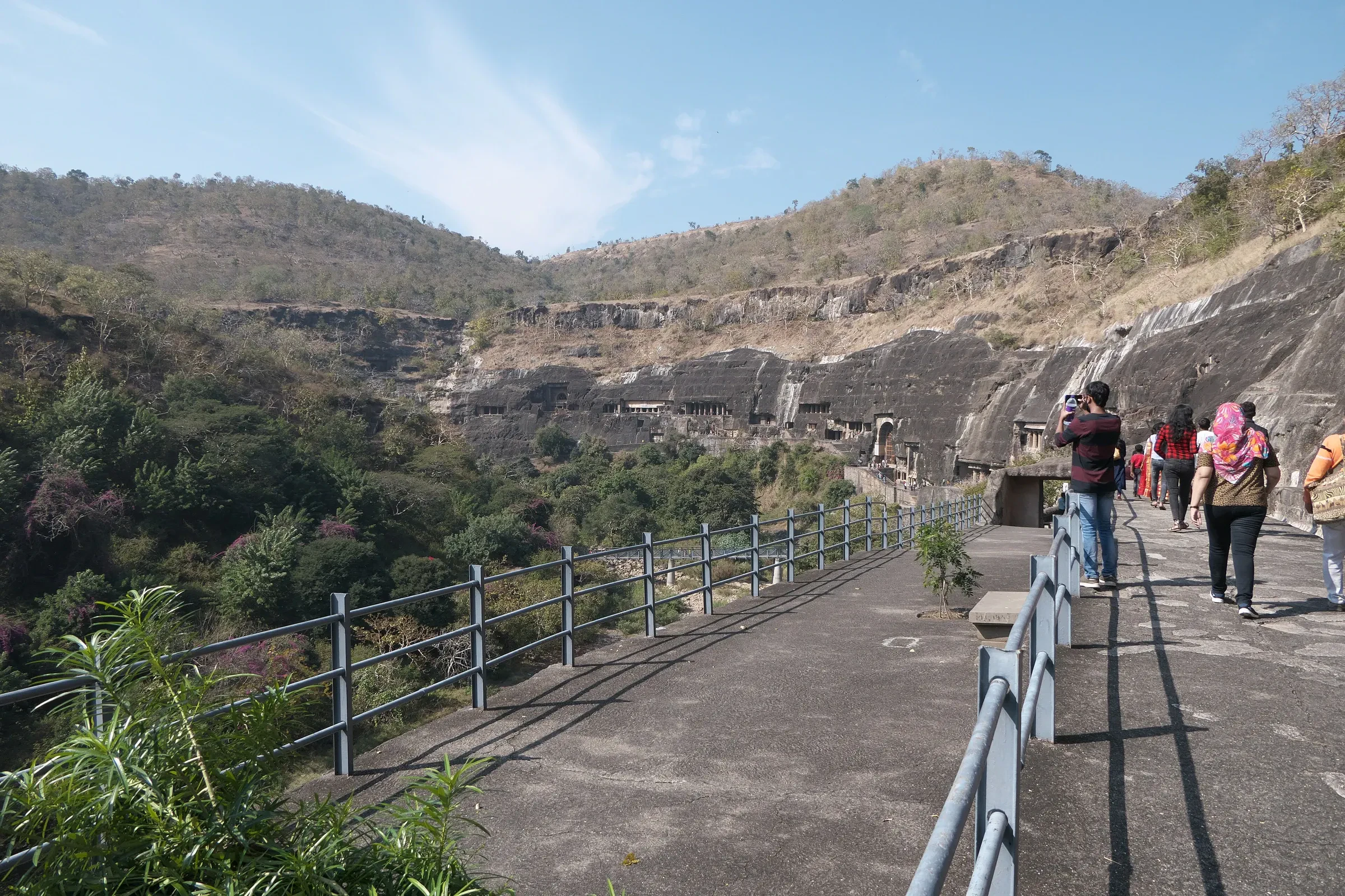 Visitors walking along a path above the gorge towards the Ajanta Caves