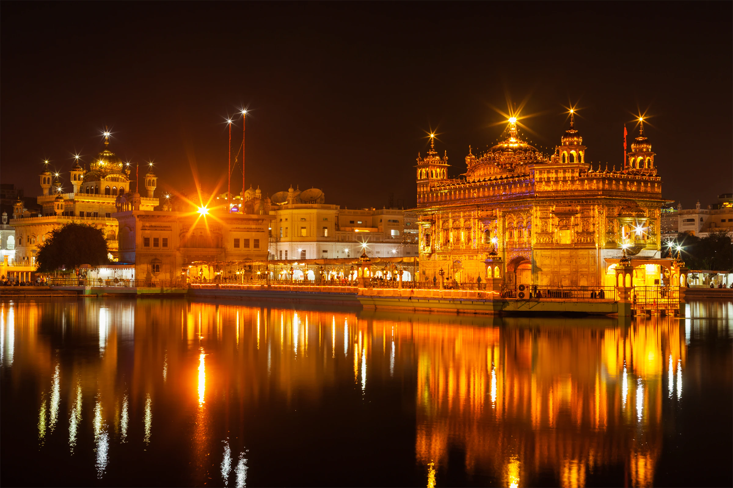 The Golden Temple lit up at night, its dome reflected in the sacred pool