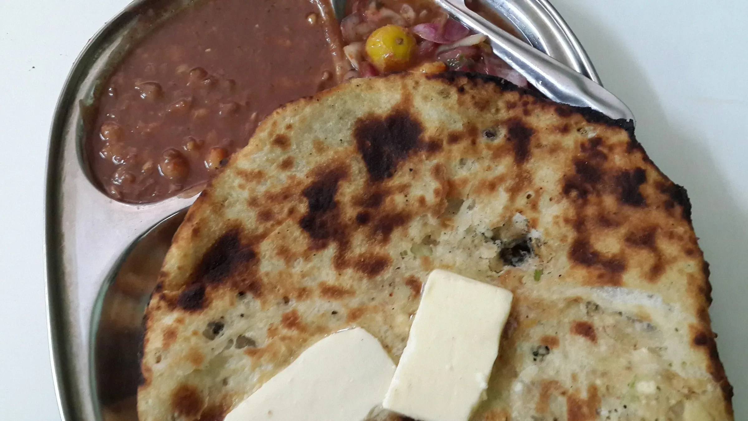 A stuffed Amritsari kulcha served with chickpea curry and a slab of butter