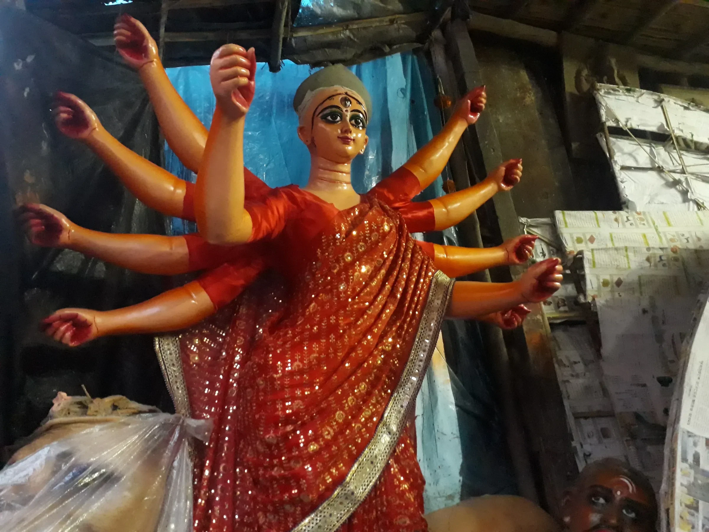 A painted clay Durga idol with raised arms in a Kumartuli workshop in Kolkata