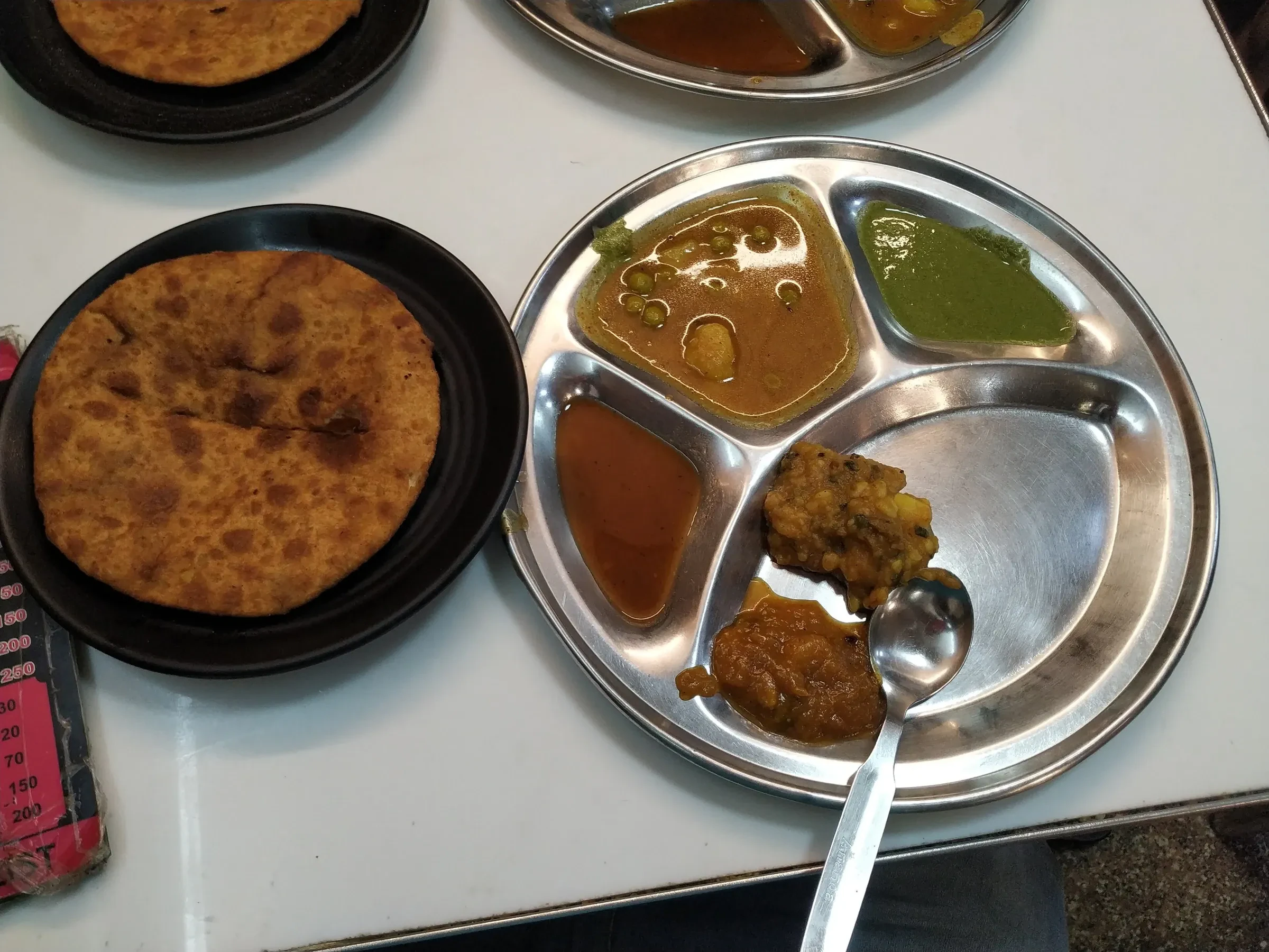 Stuffed paranthe with sabzi and chutneys on a steel thali in Old Delhi