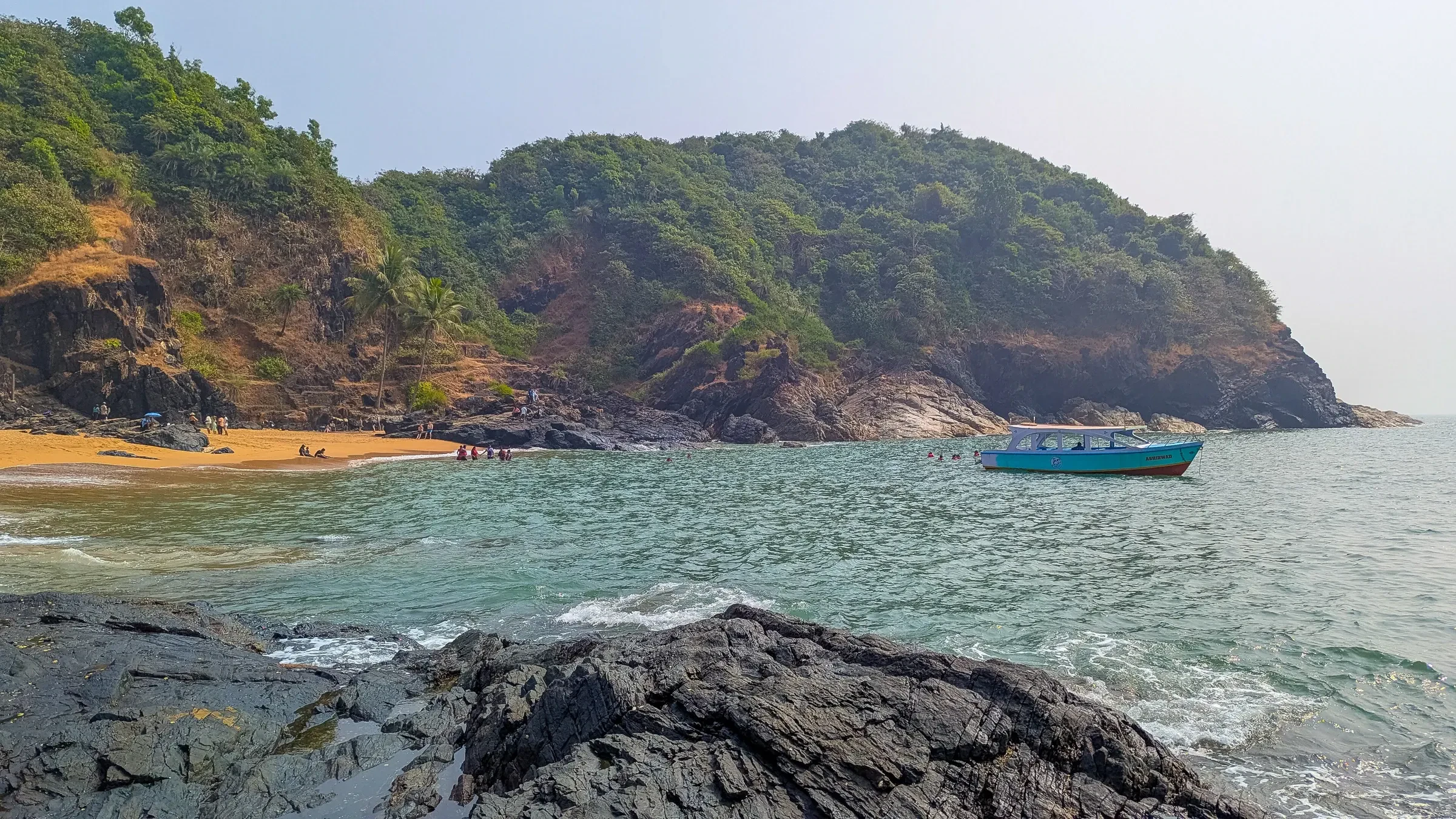 A boat anchored below a rocky headland on the Paradise Beach trail near Gokarna