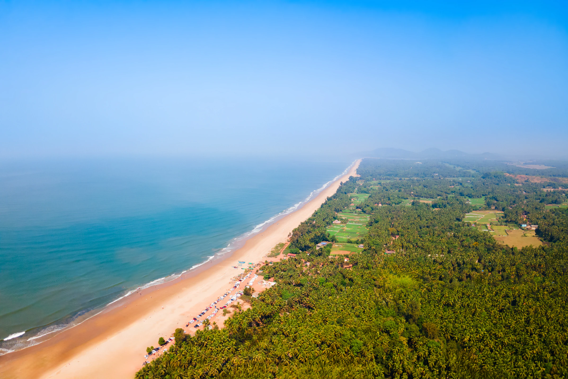 A long palm-backed stretch of Gokarna beach seen from the air