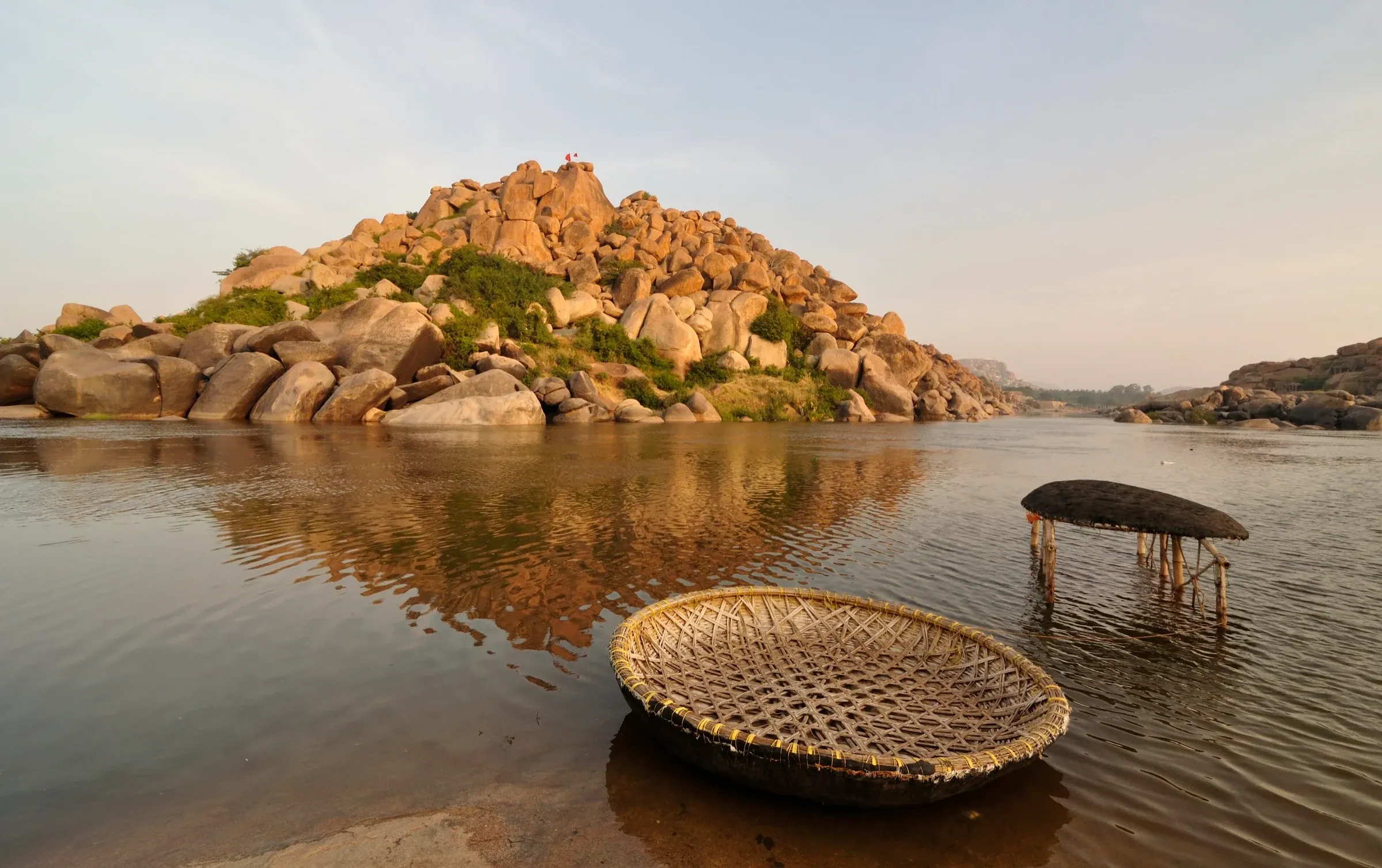 Two round coracle boats on the Tungabhadra River with boulders behind