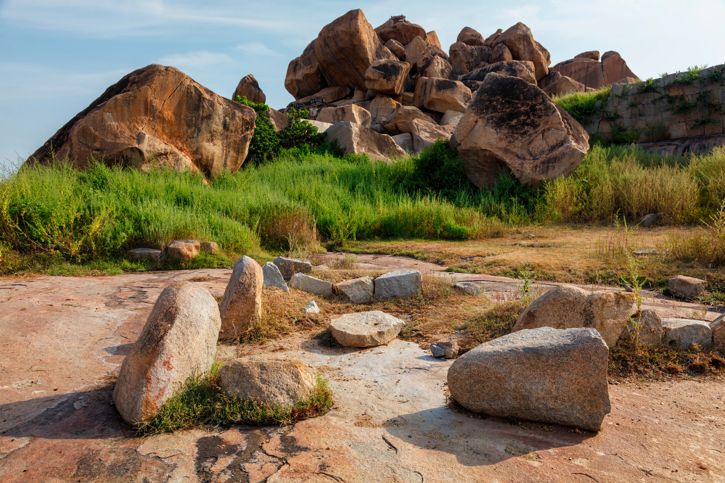 Giant granite boulders and grass on the rocky ground at Hampi