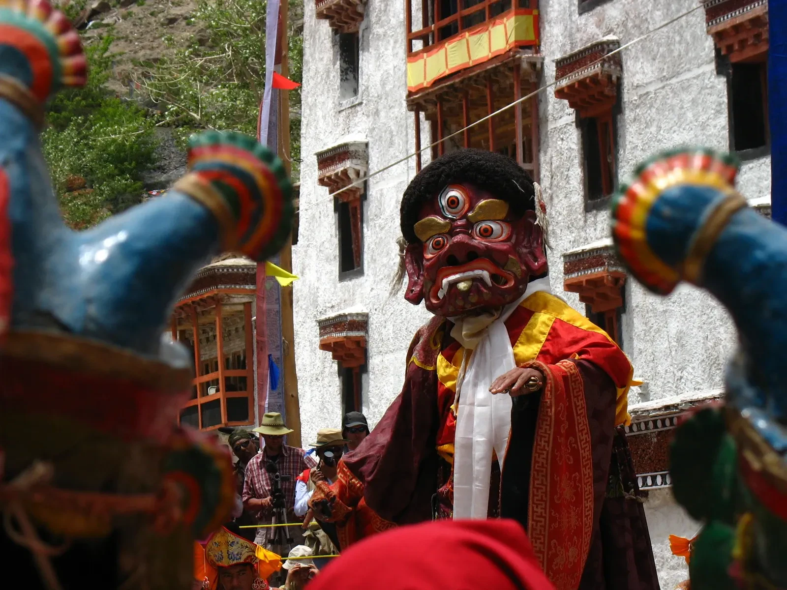A masked monk in brocade robes in the courtyard at a Hemis Monastery festival