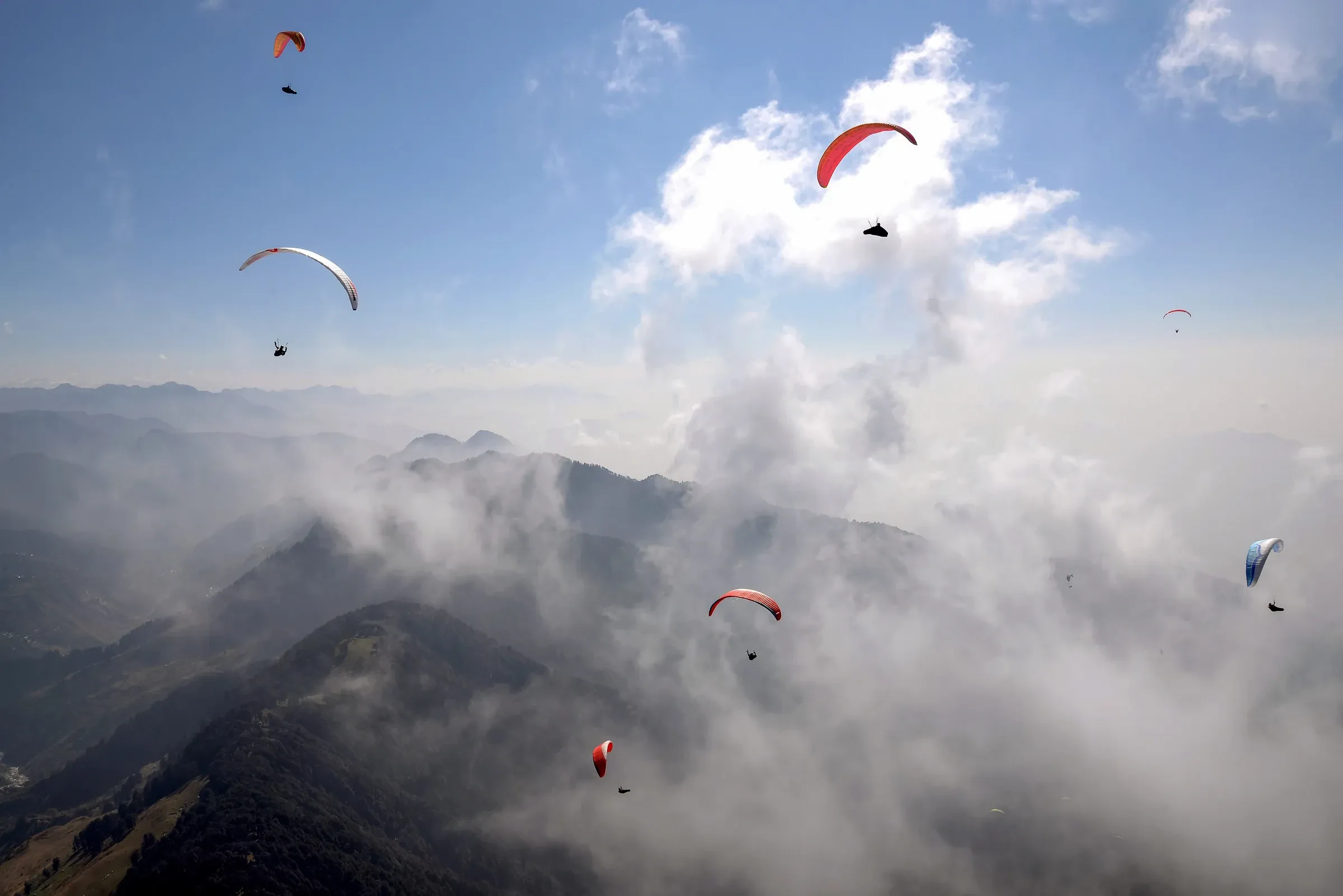 Paragliders in the air over cloud-filled valleys at Bir Billing, Himachal Pradesh
