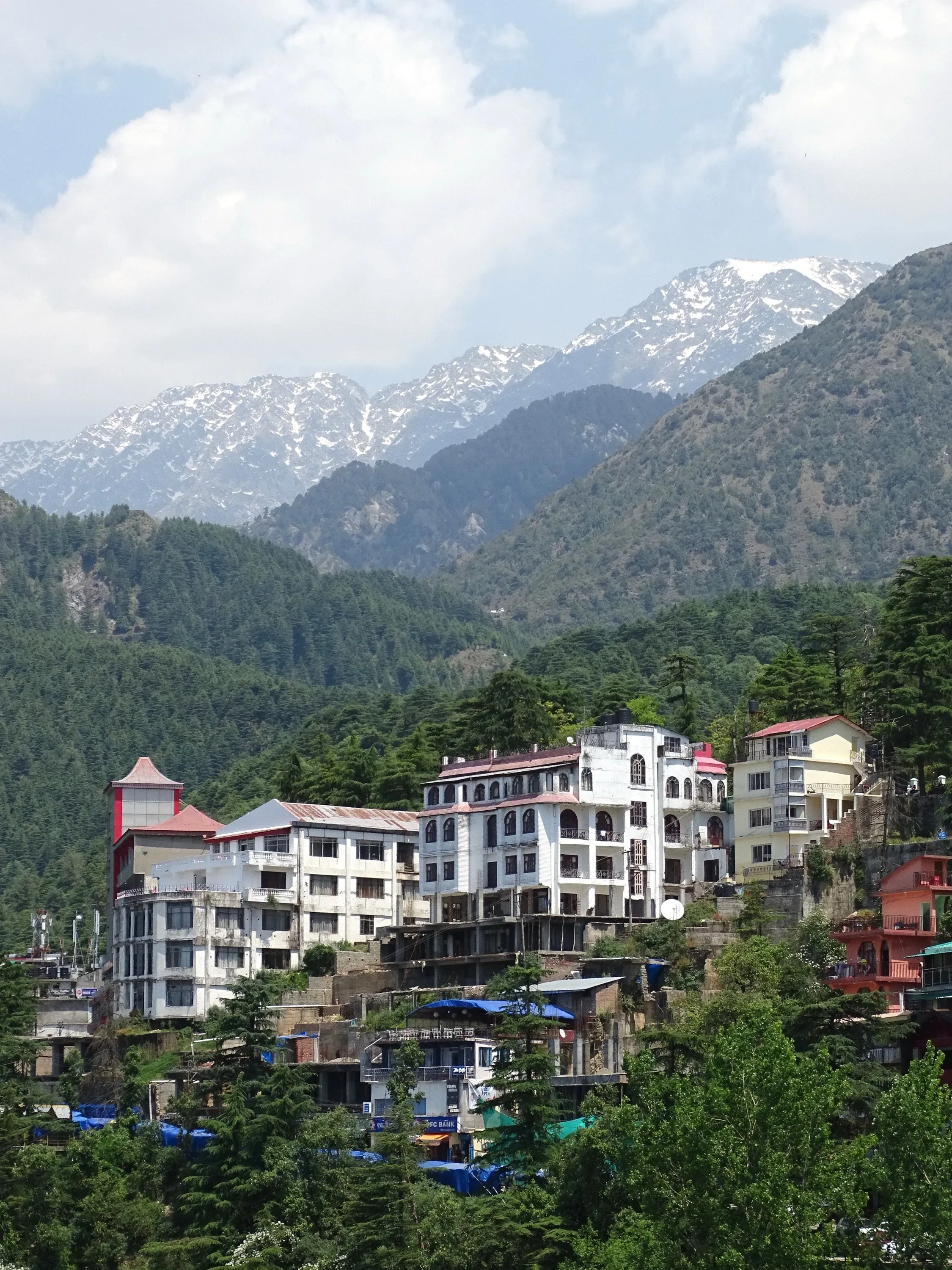 The hillside buildings of McLeod Ganj below snow-capped peaks, seen from the Tsuglagkhang Complex