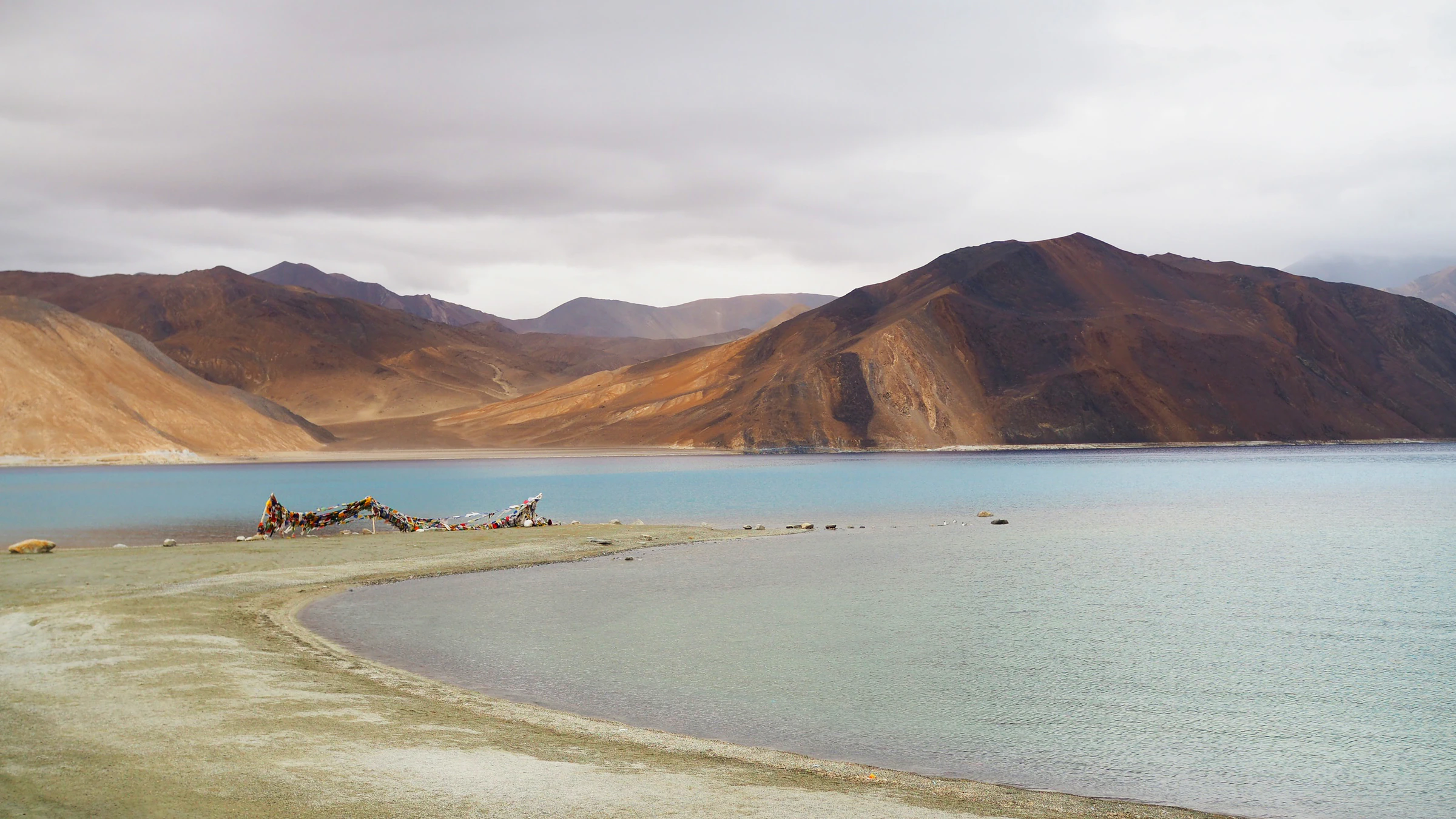 Pangong Lake in Ladakh, a pale shoreline below brown mountains