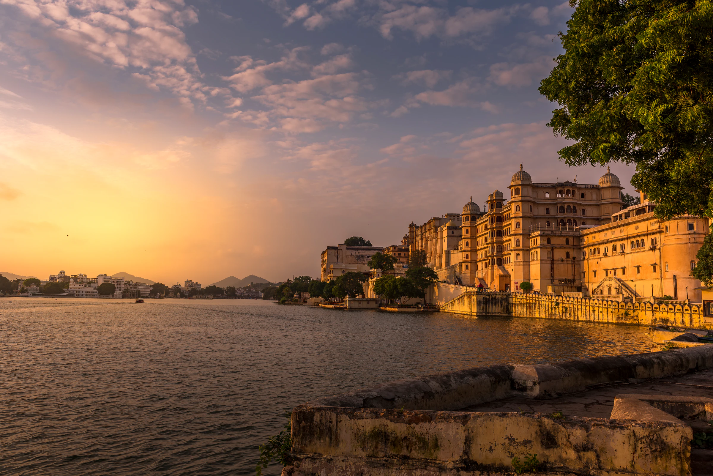 Boats on Lake Pichola at sunset, with Udaipur's City Palace above the water