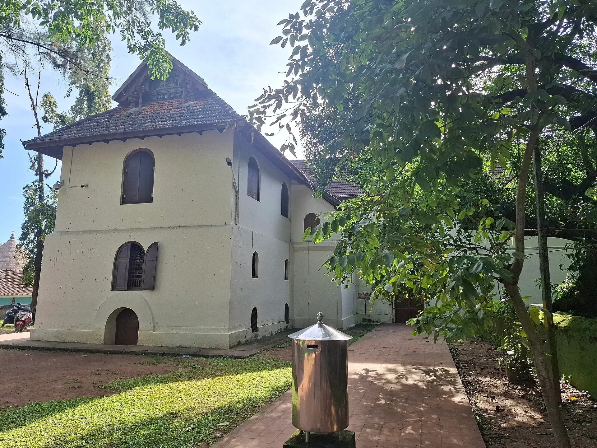 Mattancherry Palace, a cream-coloured building with a Kerala-style tiled roof, seen from its garden