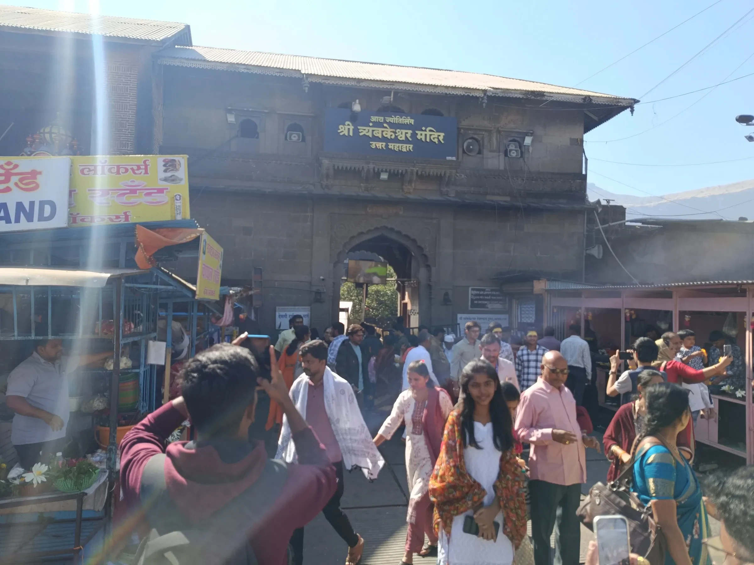 Pilgrims in everyday clothes walking past the entrance gate of Trimbakeshwar Shiva Temple