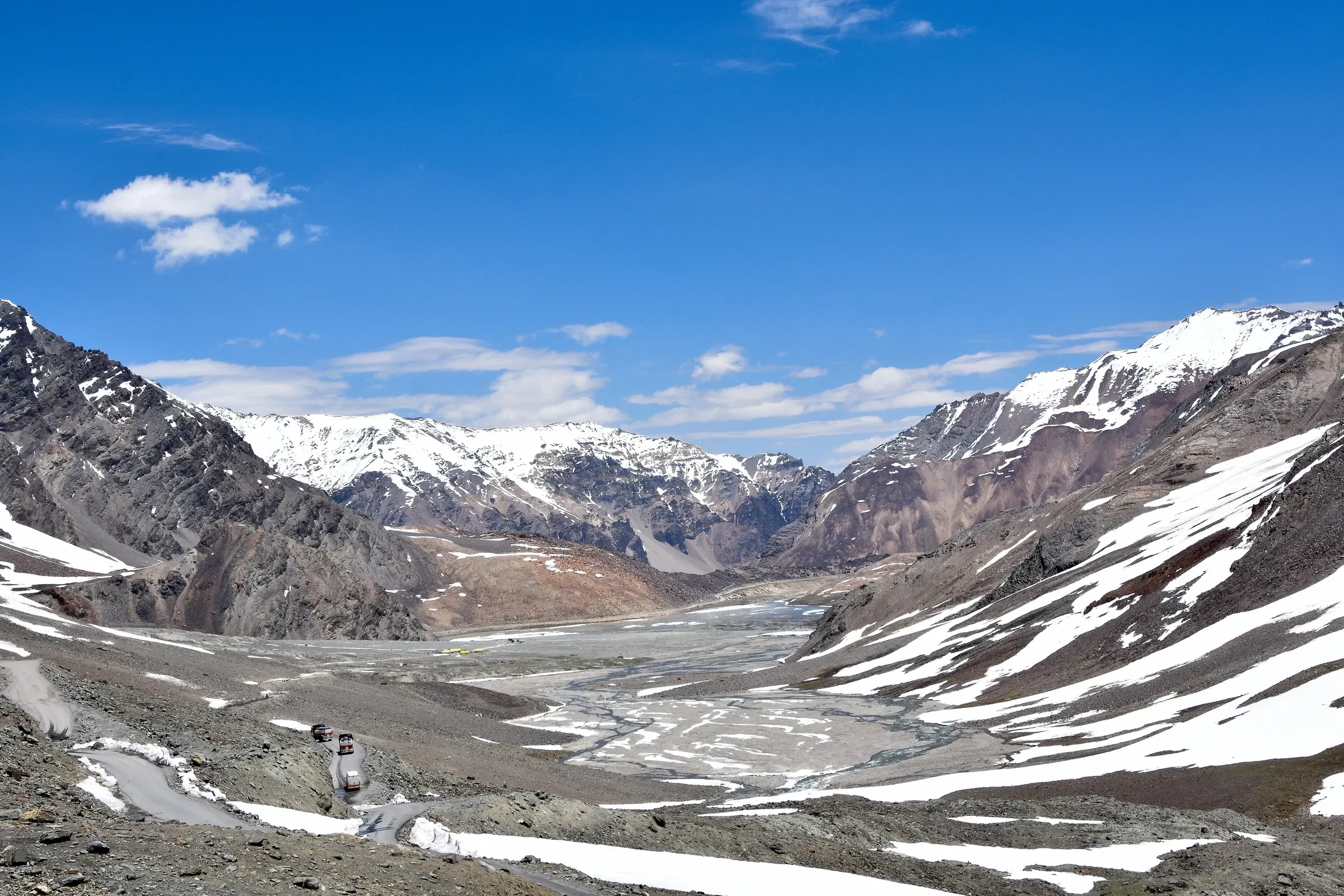 Snow-streaked slopes and a braided stream below Baralacha La, on the road from Manali towards Leh