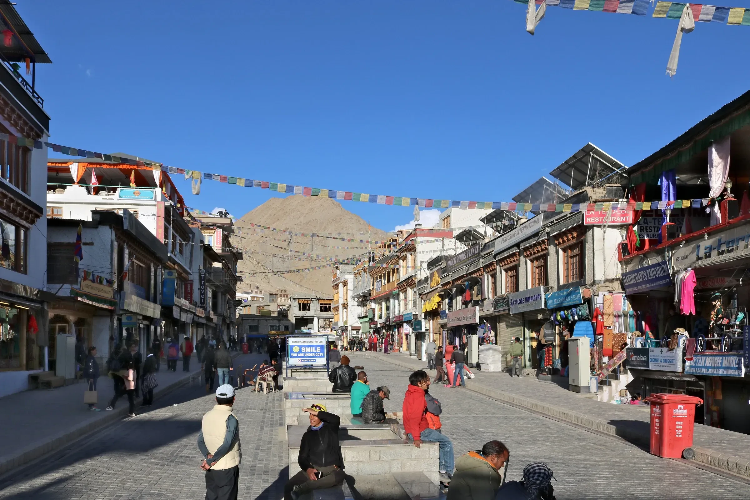 Shops, prayer flags and people strolling along Leh's Main Bazaar road