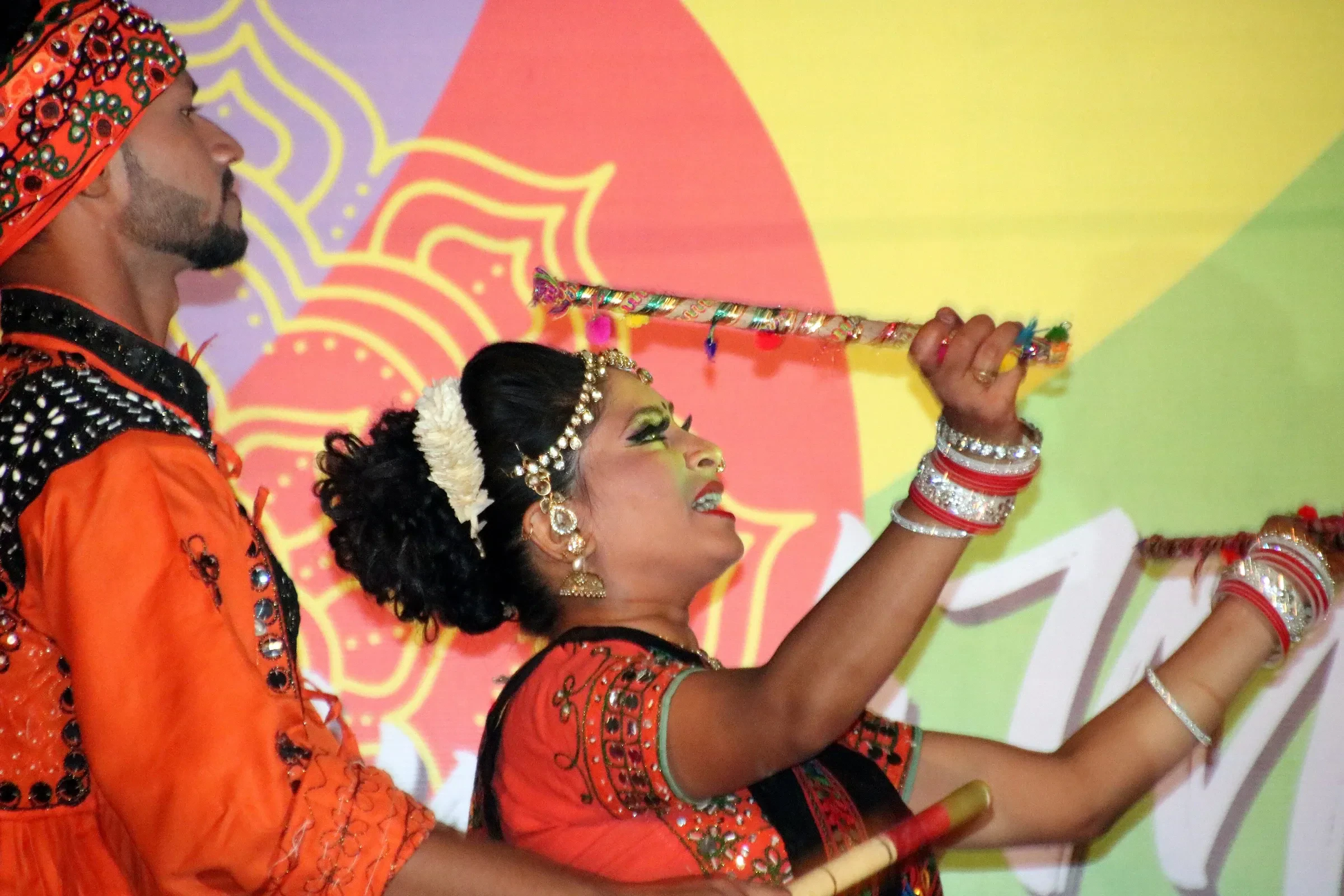 A pair of performers in traditional costume dancing Dandiya Raas with decorated sticks