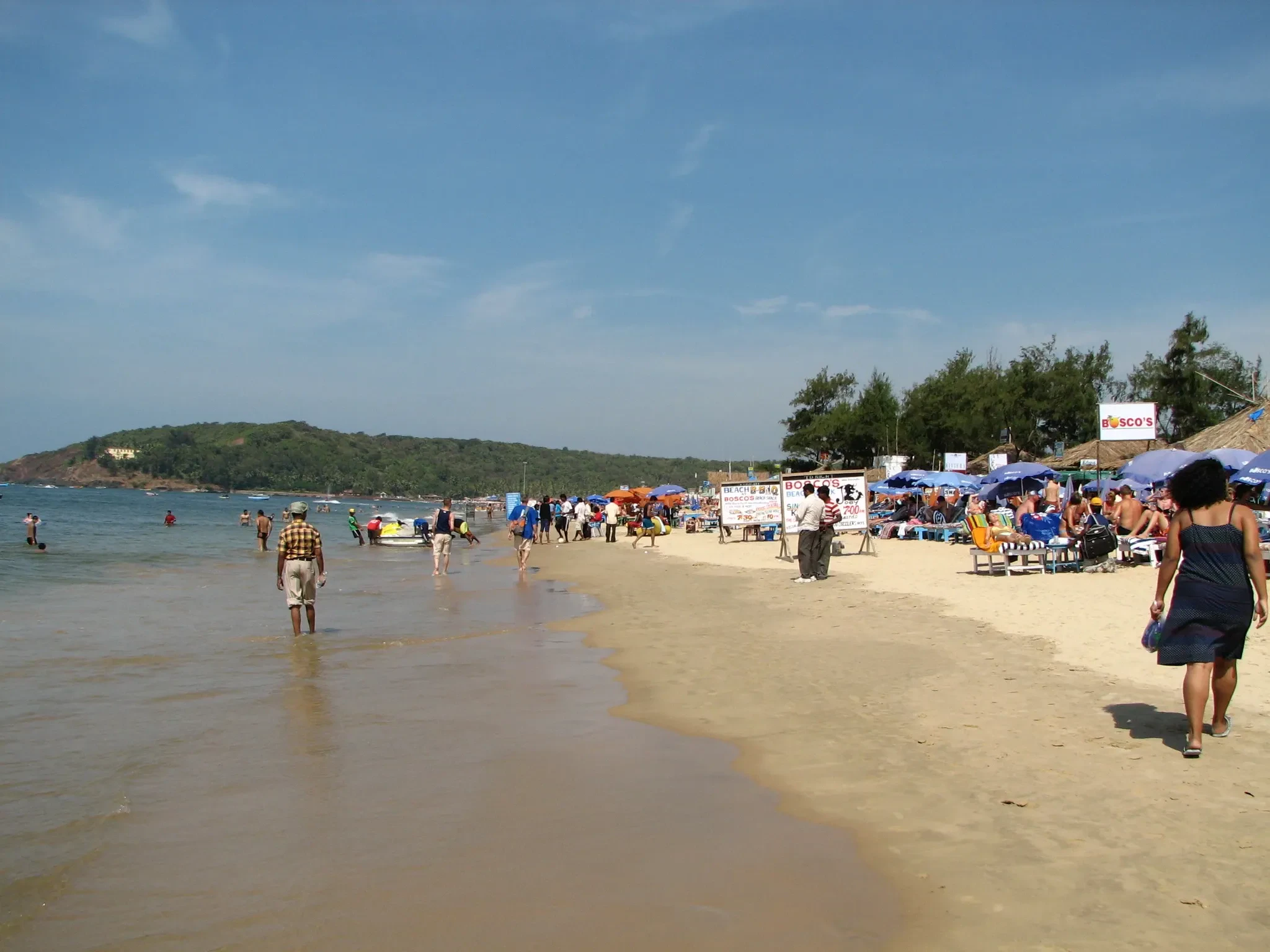 A crowded stretch of Baga beach in North Goa with umbrellas and visitors on the sand