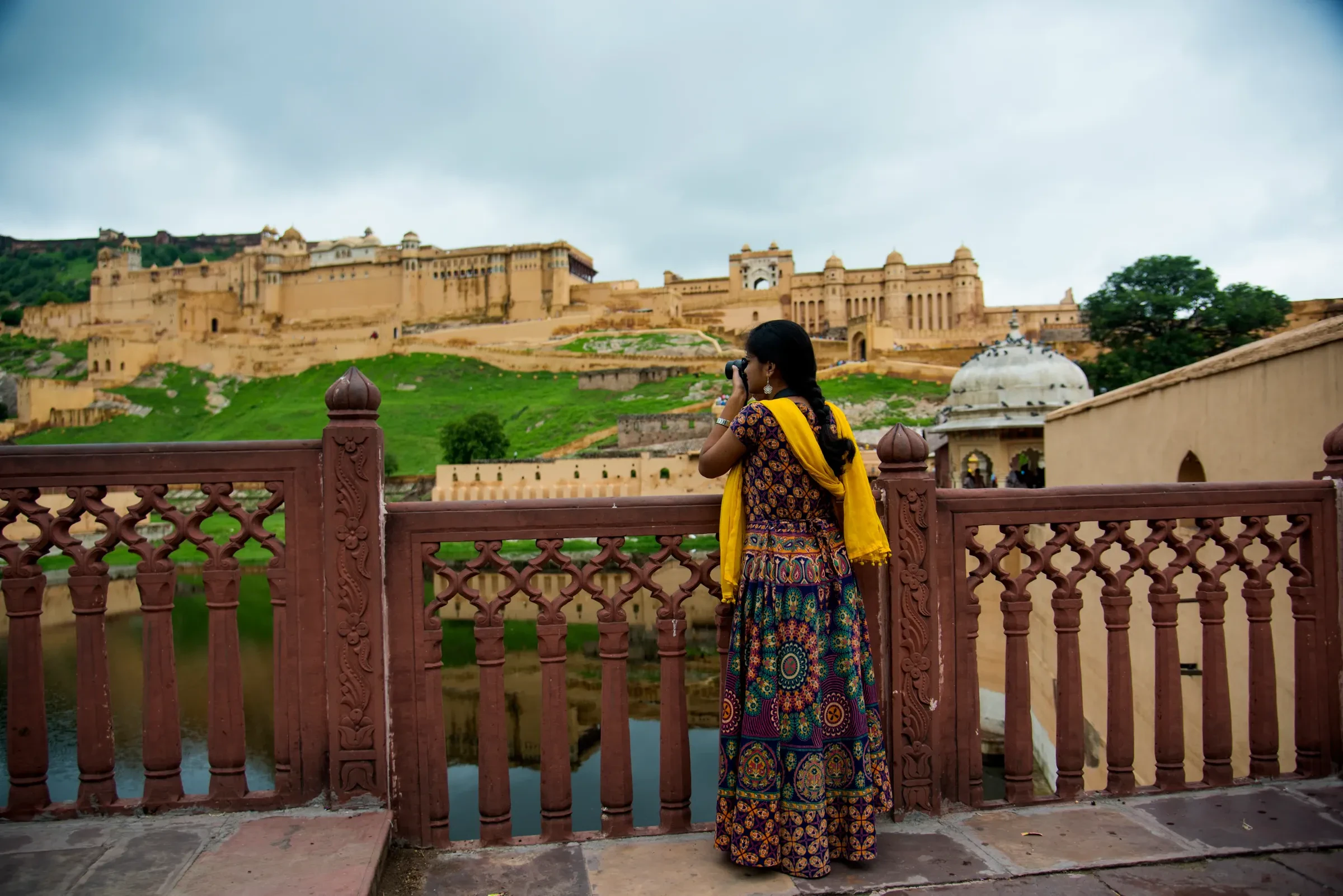 A woman in a yellow scarf looking out at Amer Fort near Jaipur, Rajasthan