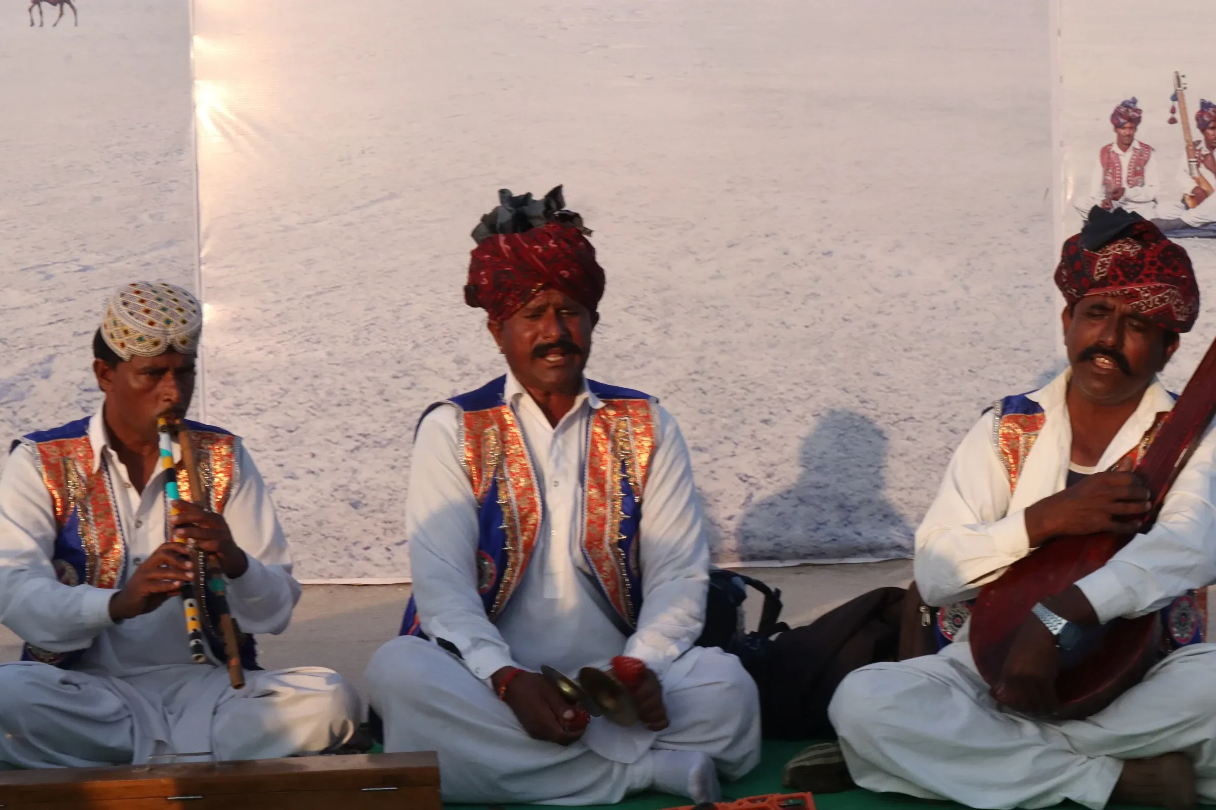 Three Kutchi musicians in turbans playing a wind instrument and a string instrument at Rann Utsav