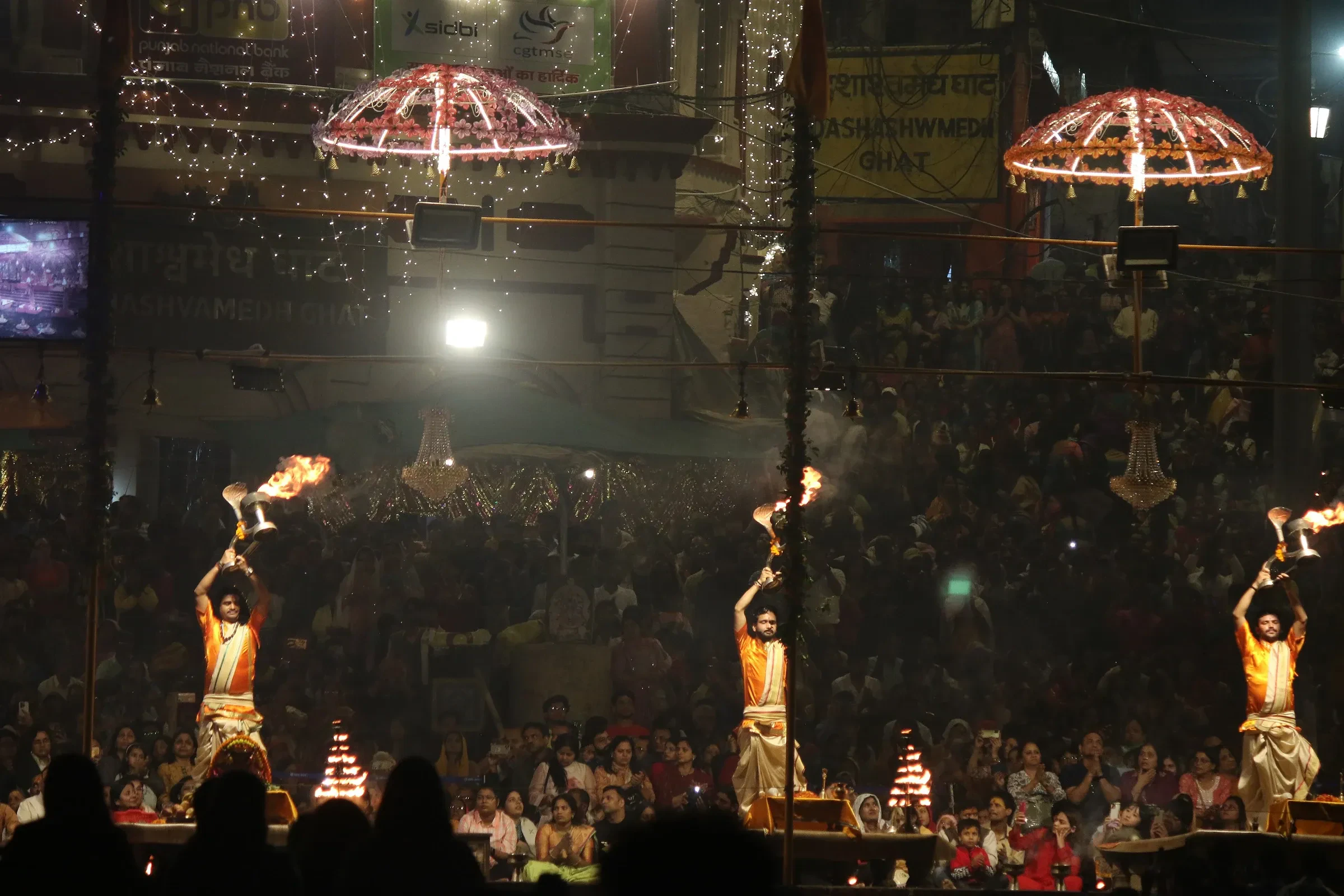 Priests holding flaming lamps during the evening Ganga aarti at Dashashwamedh Ghat, Varanasi