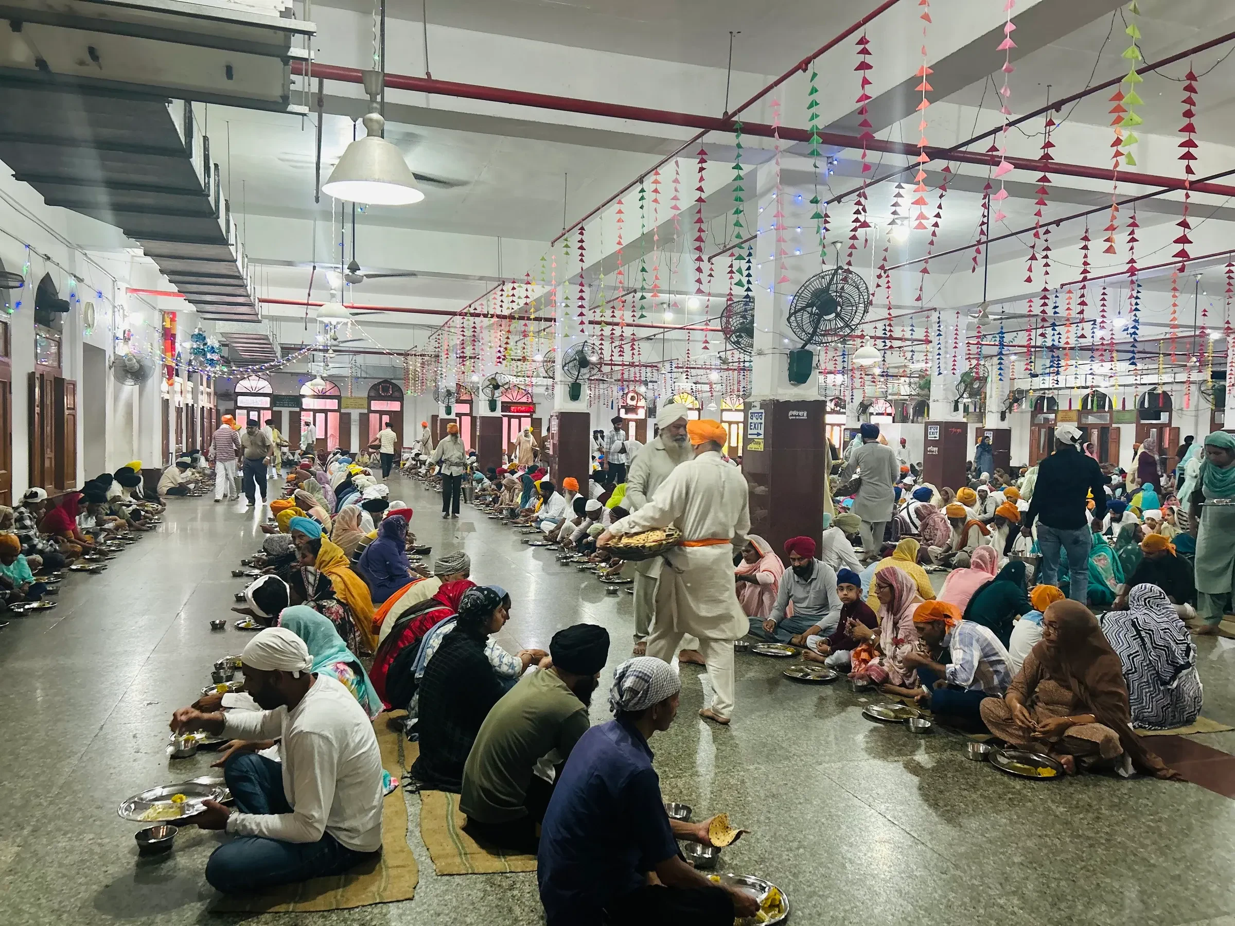 Visitors sitting in rows to eat in the langar hall at the Golden Temple, Amritsar
