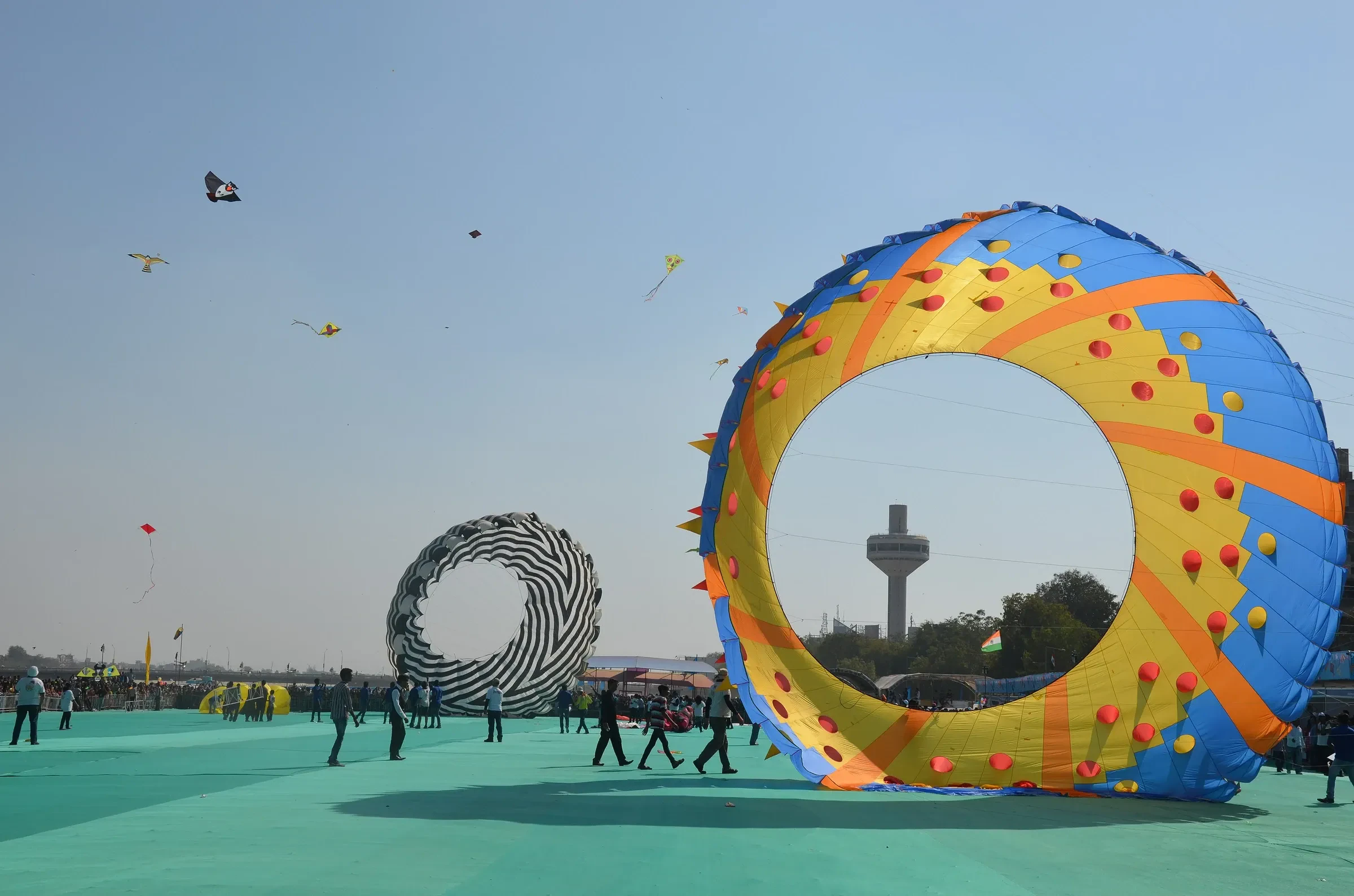 A giant ring-shaped kite and smaller kites over a festival ground in India