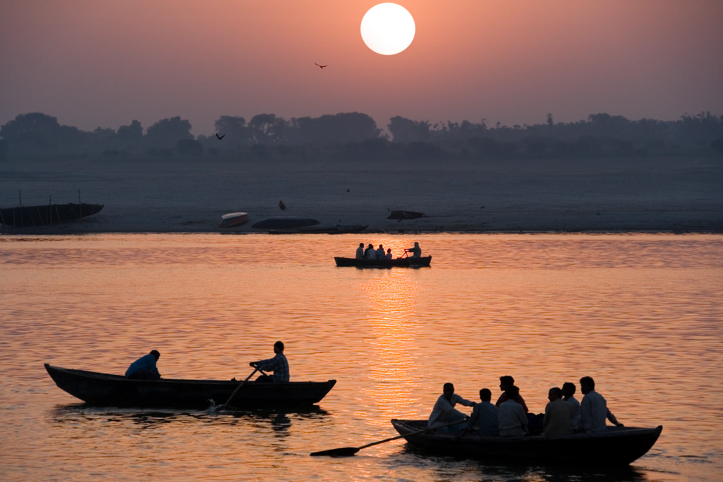 Rowing boats on the Ganges in Varanasi with the sun low over the water
