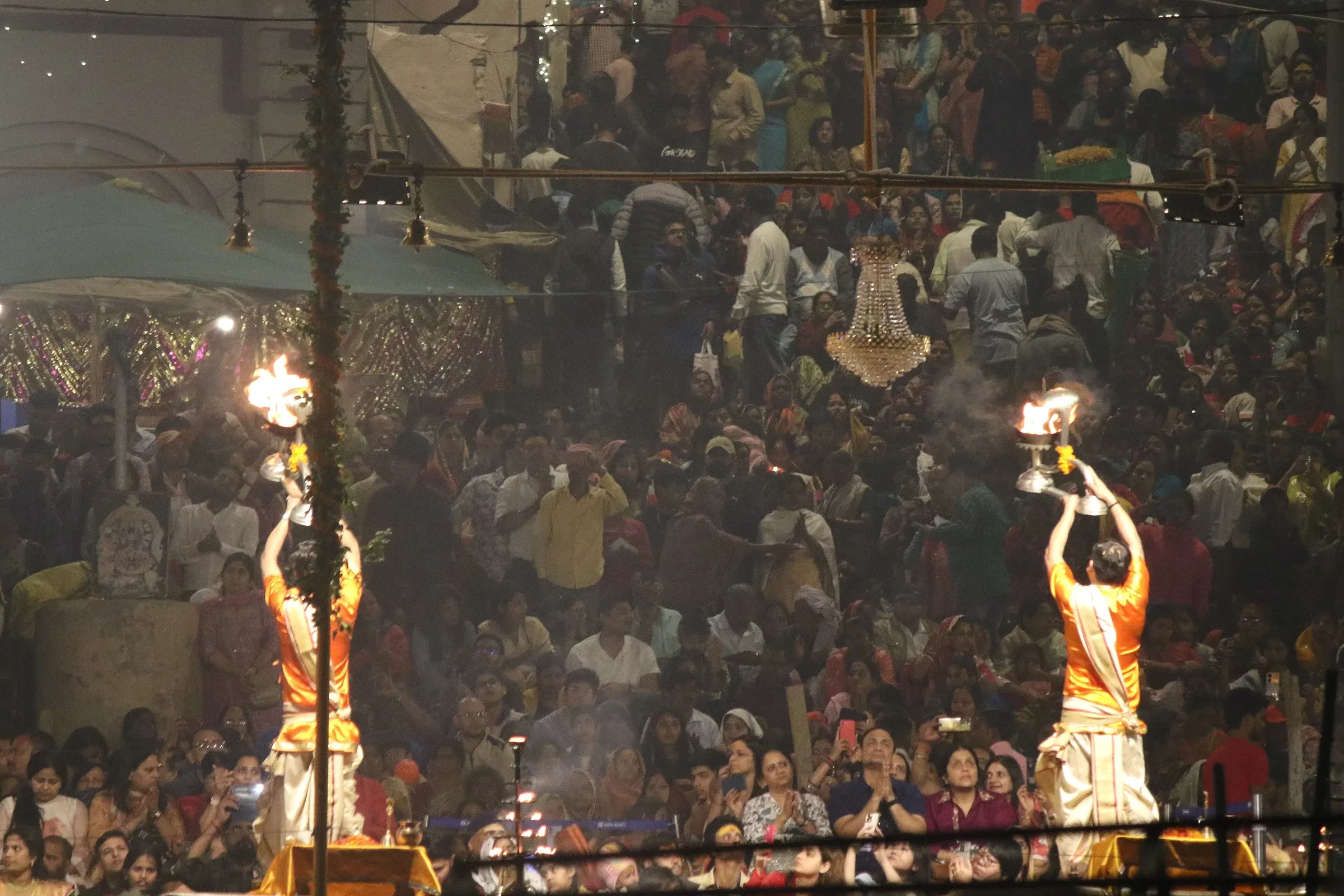 Priests holding fire lamps in front of a packed crowd at the evening Ganga aarti in Varanasi