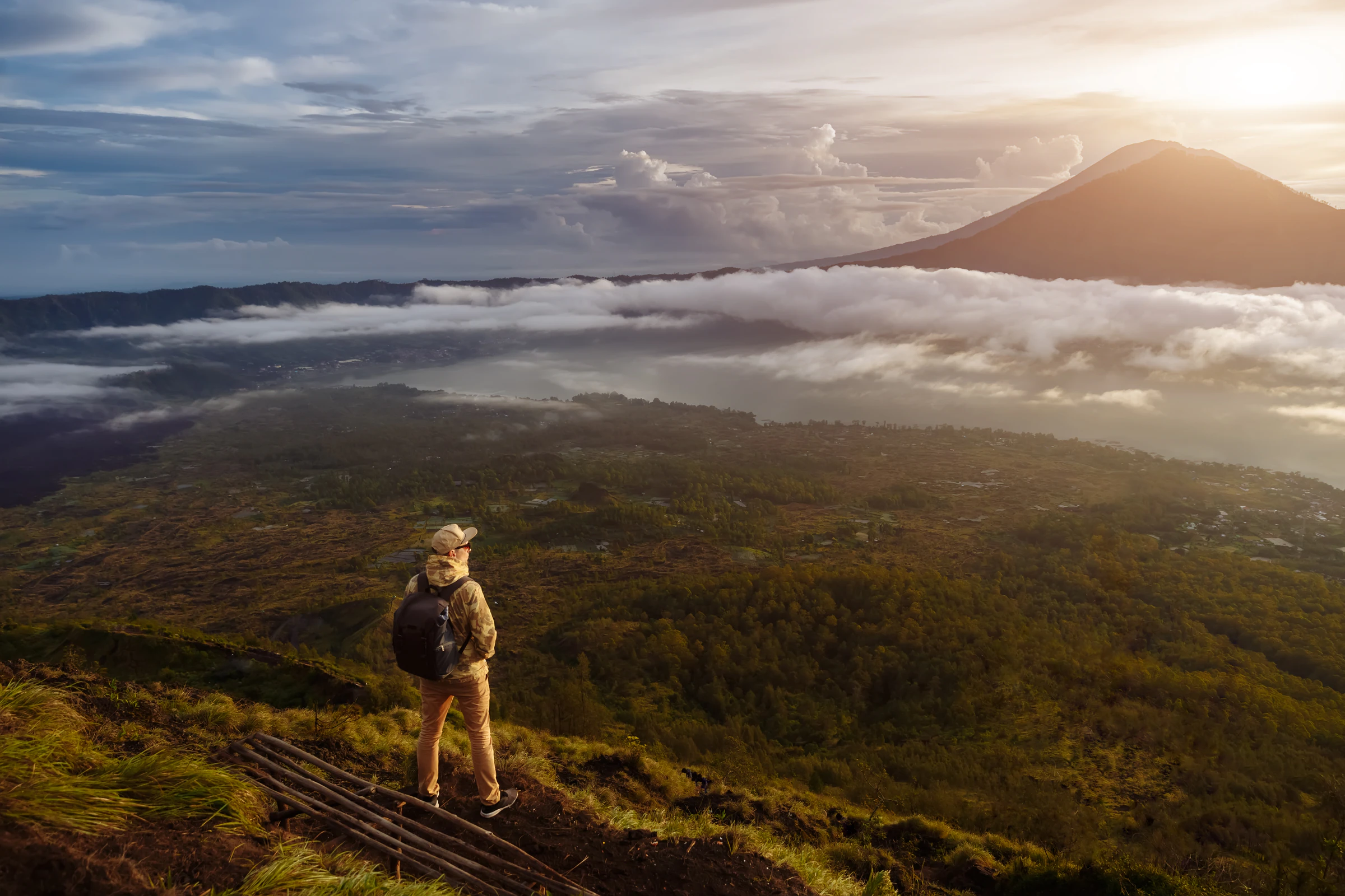 A hiker on the rim of Mount Batur at sunrise, above the clouds