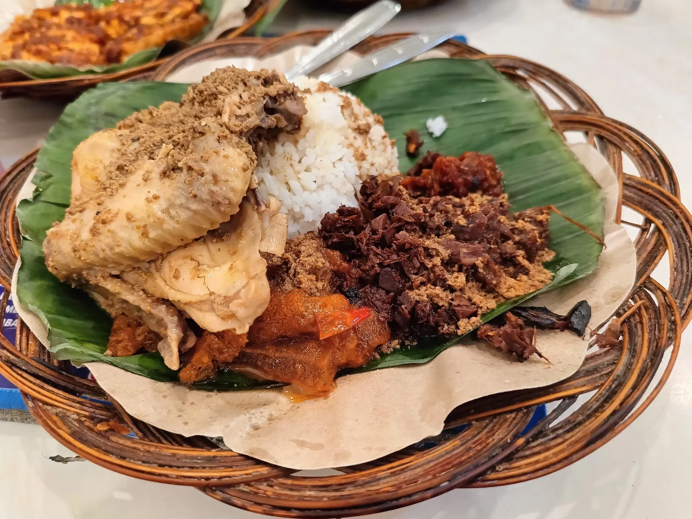 Gudeg ayam, young jackfruit stew with chicken and rice, served on banana leaf