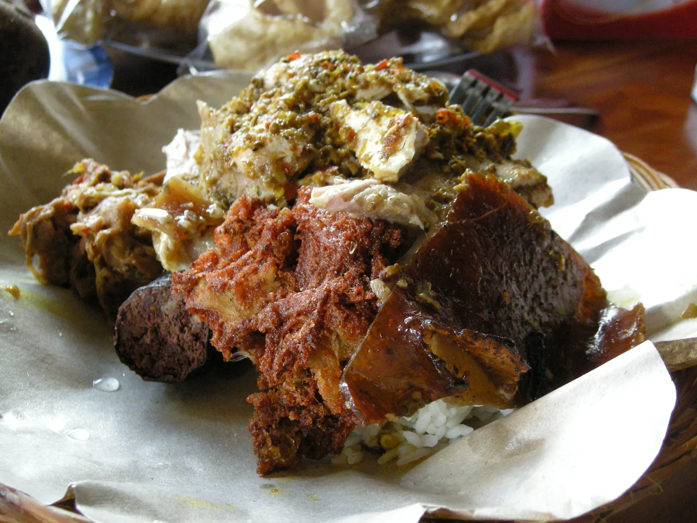 A portion of babi guling, Balinese roast pork, served on paper with rice
