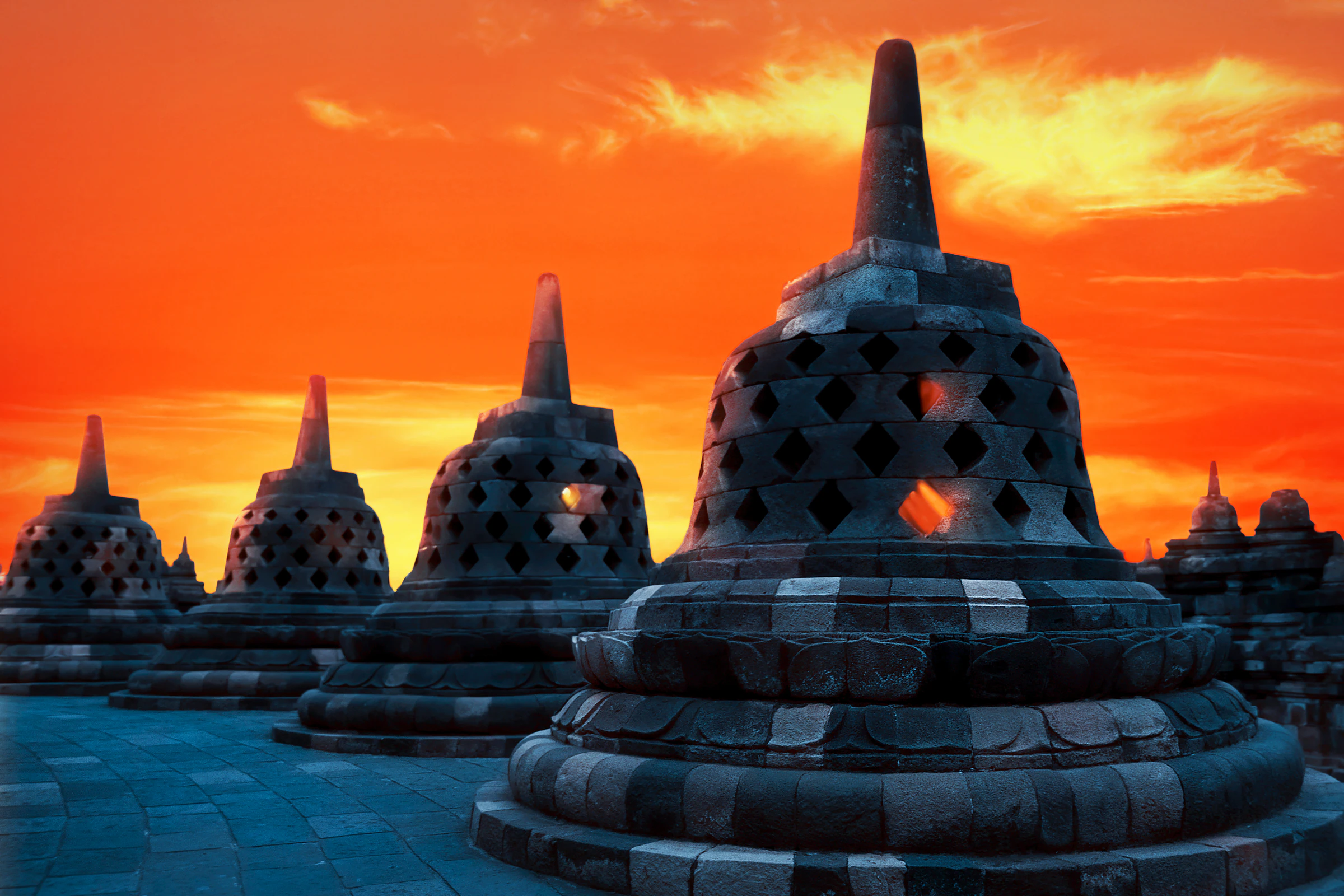 Borobudur's stupas silhouetted against an orange sunrise sky