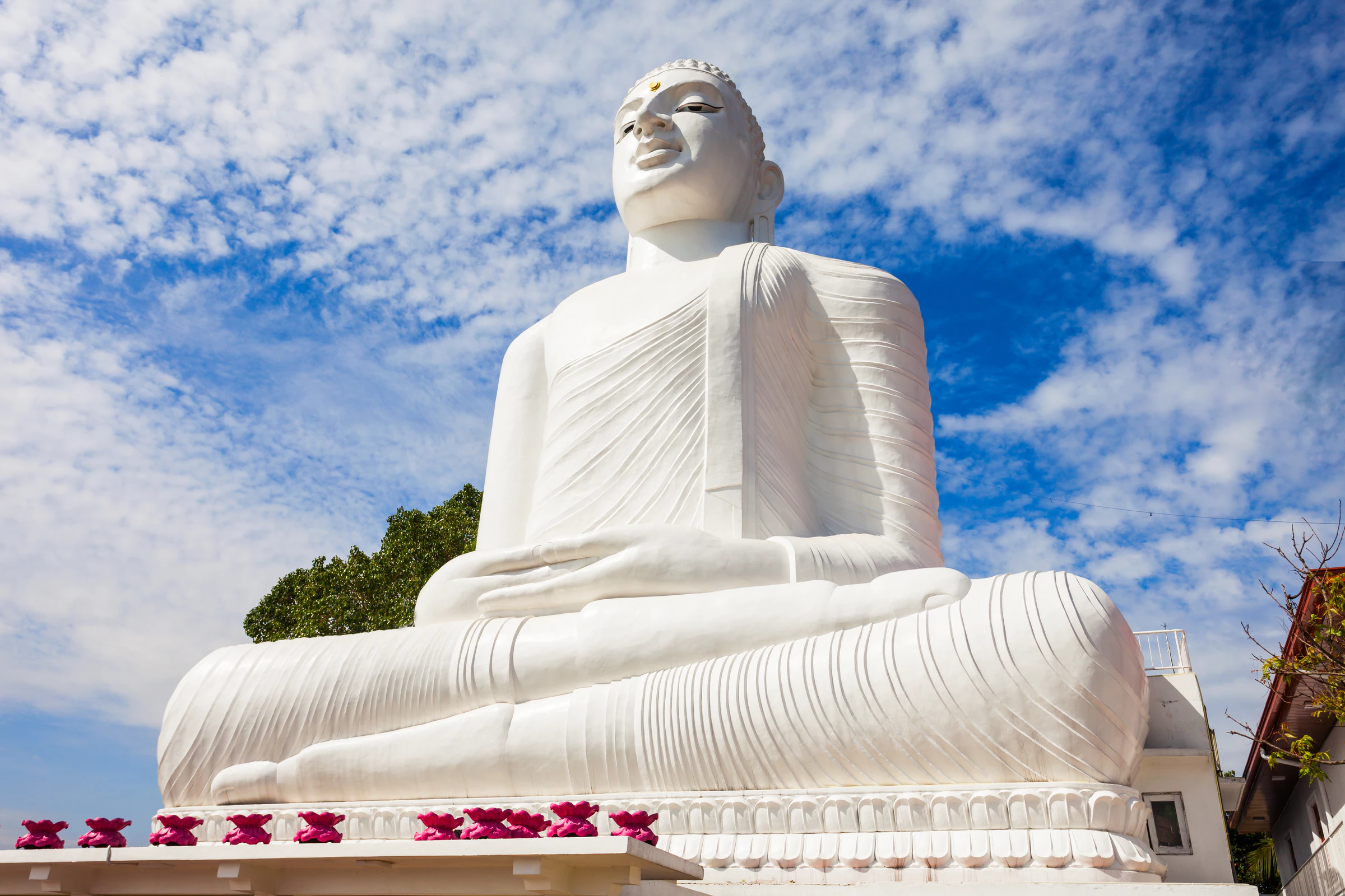 The seated white Bahirawakanda Buddha statue against a blue sky in Kandy