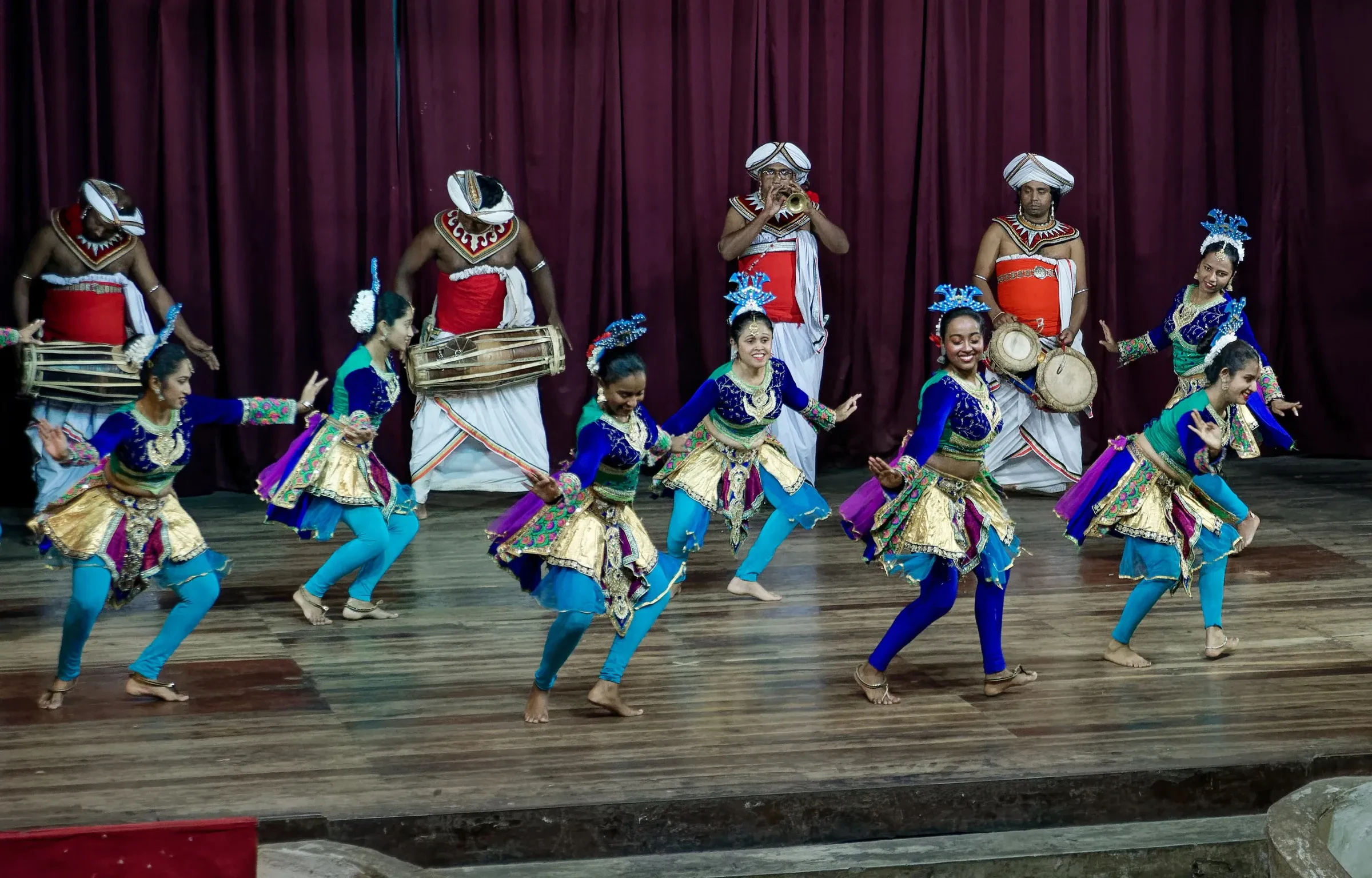 Kandyan dancers and drummers performing on a wooden stage at a cultural show in Kandy