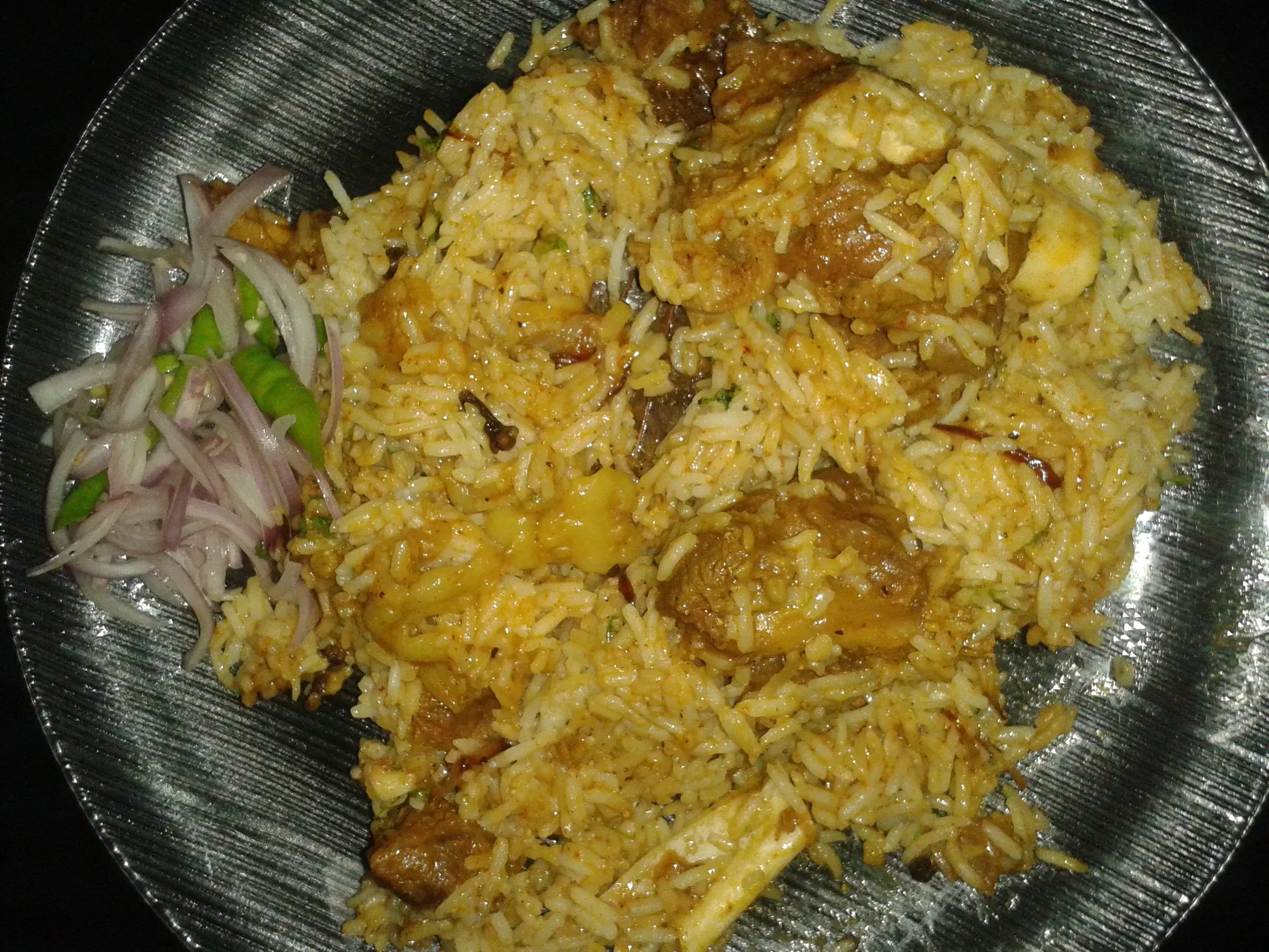 Malabar chicken biryani on a plate with sliced onions