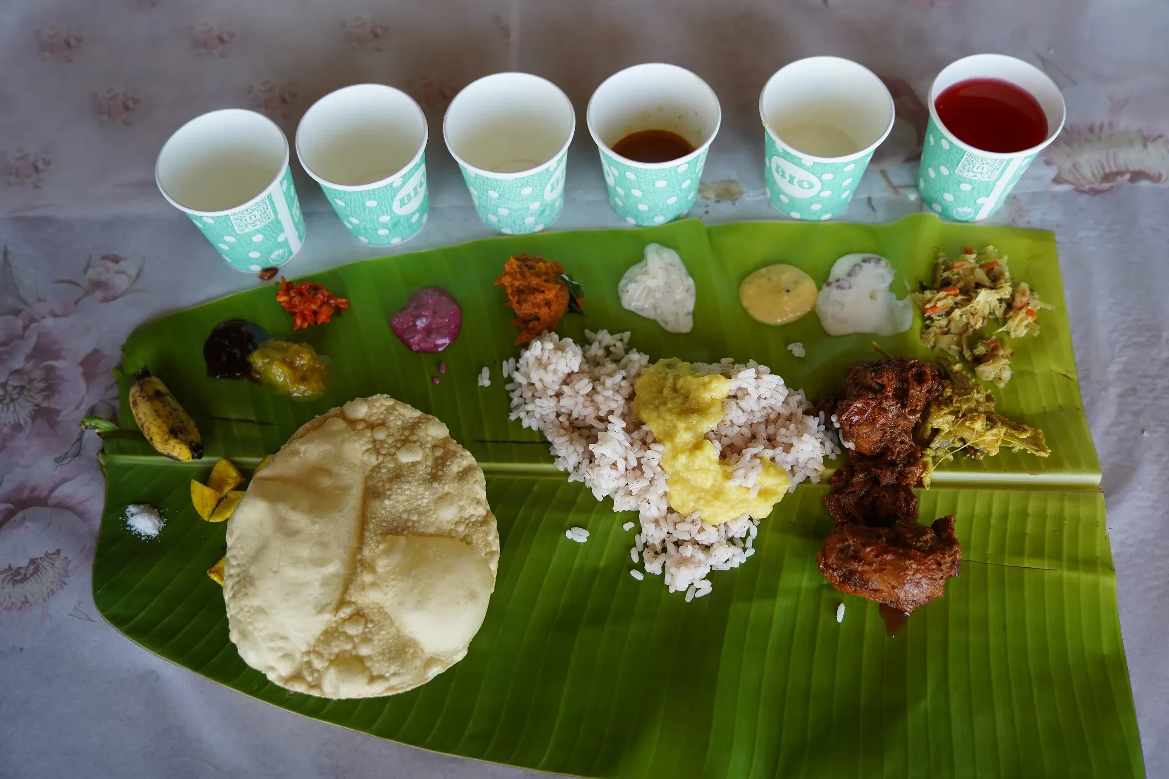 A Kerala sadya on a banana leaf with papadam, rice and small side dishes