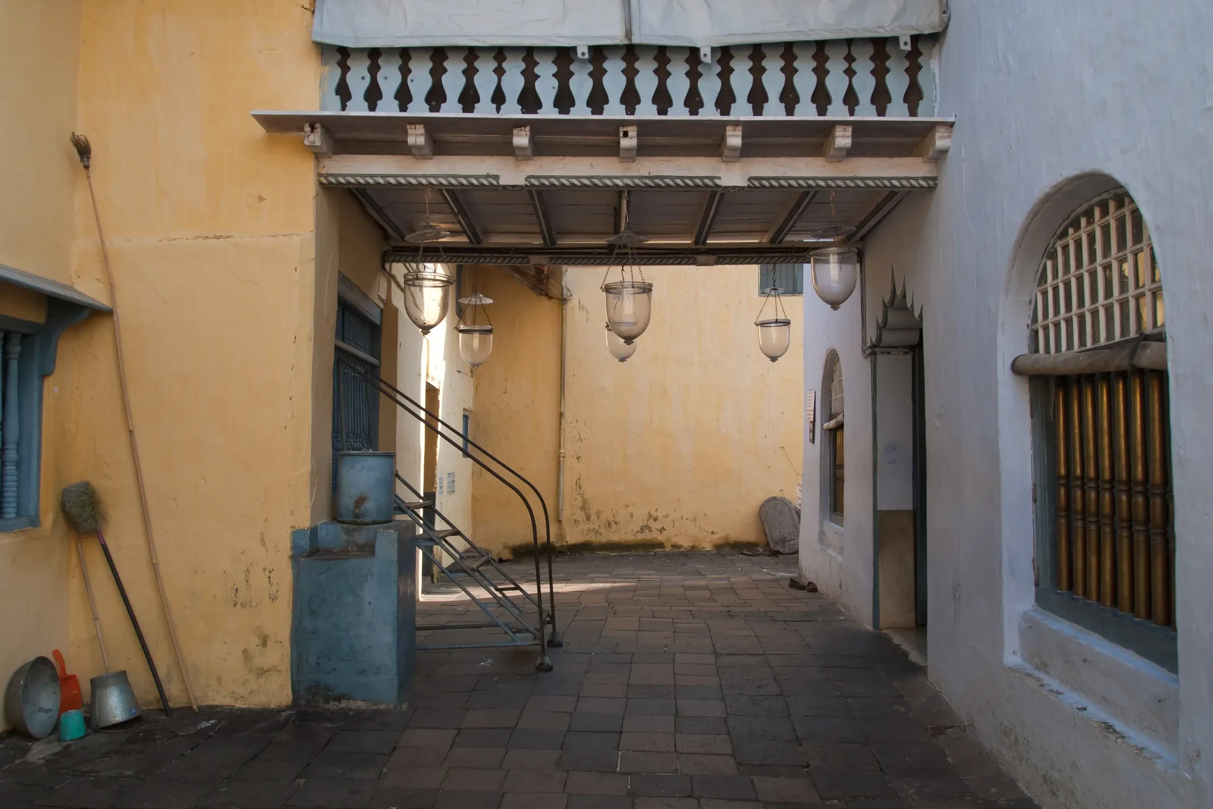 A yellow-walled courtyard with hanging lamps at the Paradesi Synagogue in Jew Town, Kochi