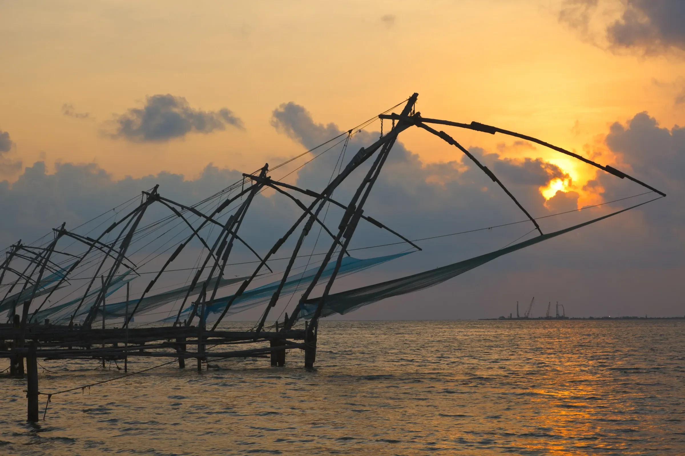 Chinese fishing nets silhouetted at sunset on Fort Kochi beach