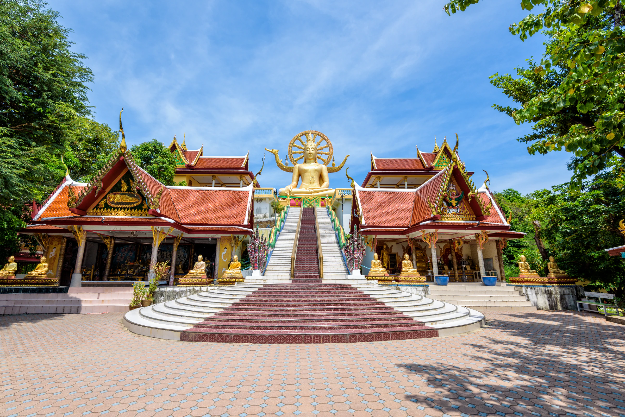 The Big Buddha at the top of a stairway between red-roofed temple halls on Koh Samui