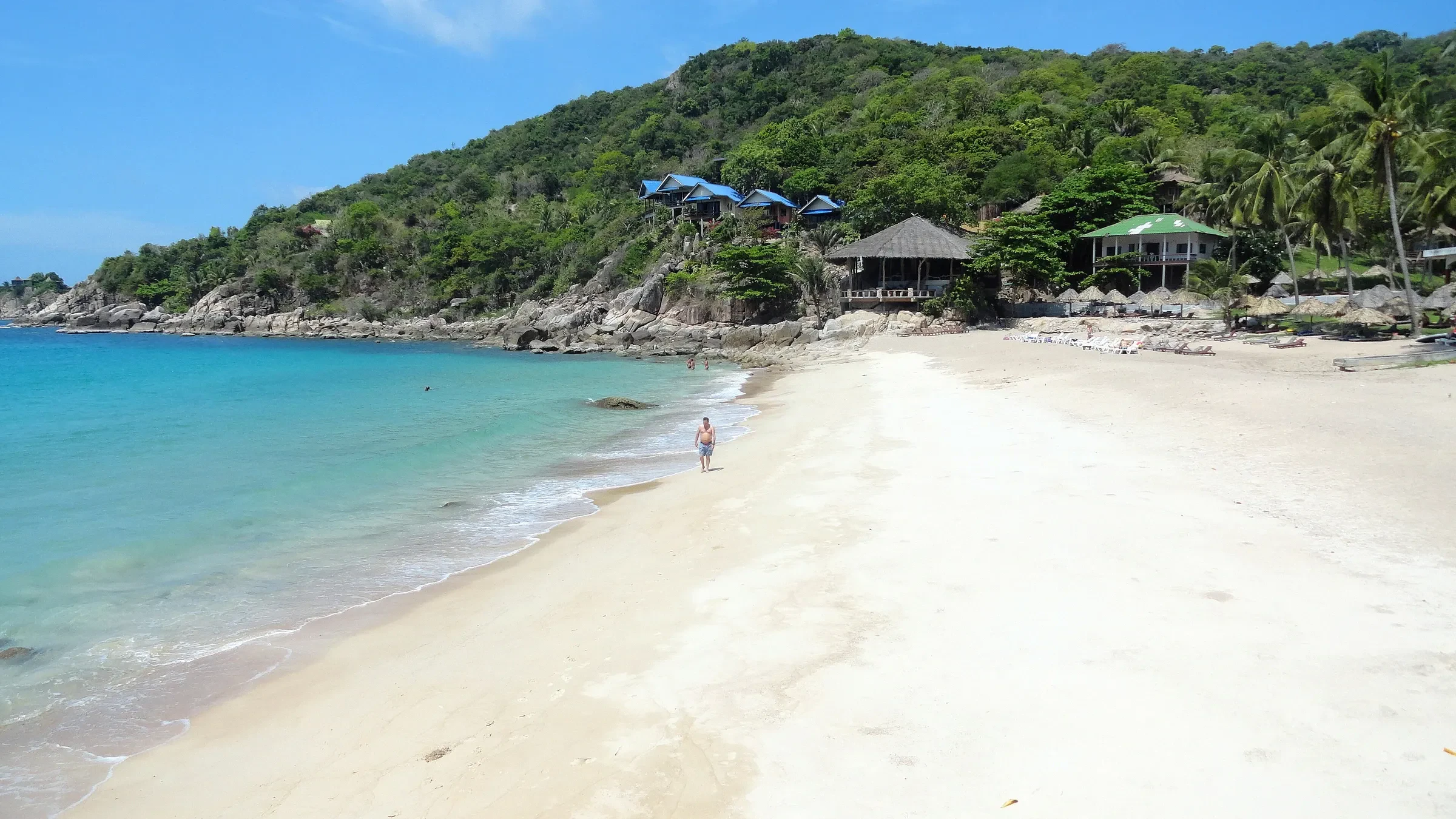 White sand and turquoise water at Aow Leuk Bay on Koh Tao, with beach bungalows on the headland