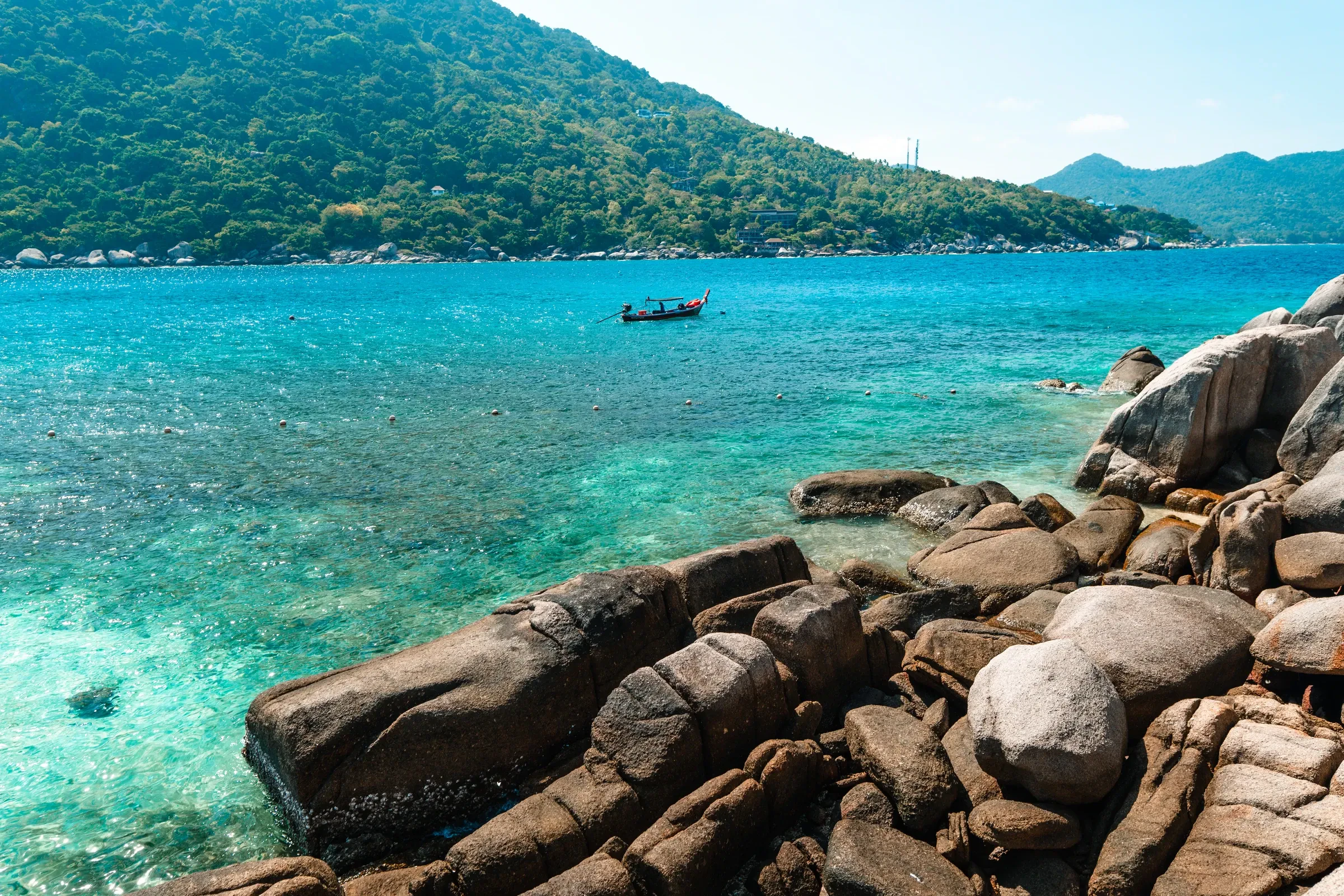 Clear turquoise water, granite boulders and green hills on Koh Tao