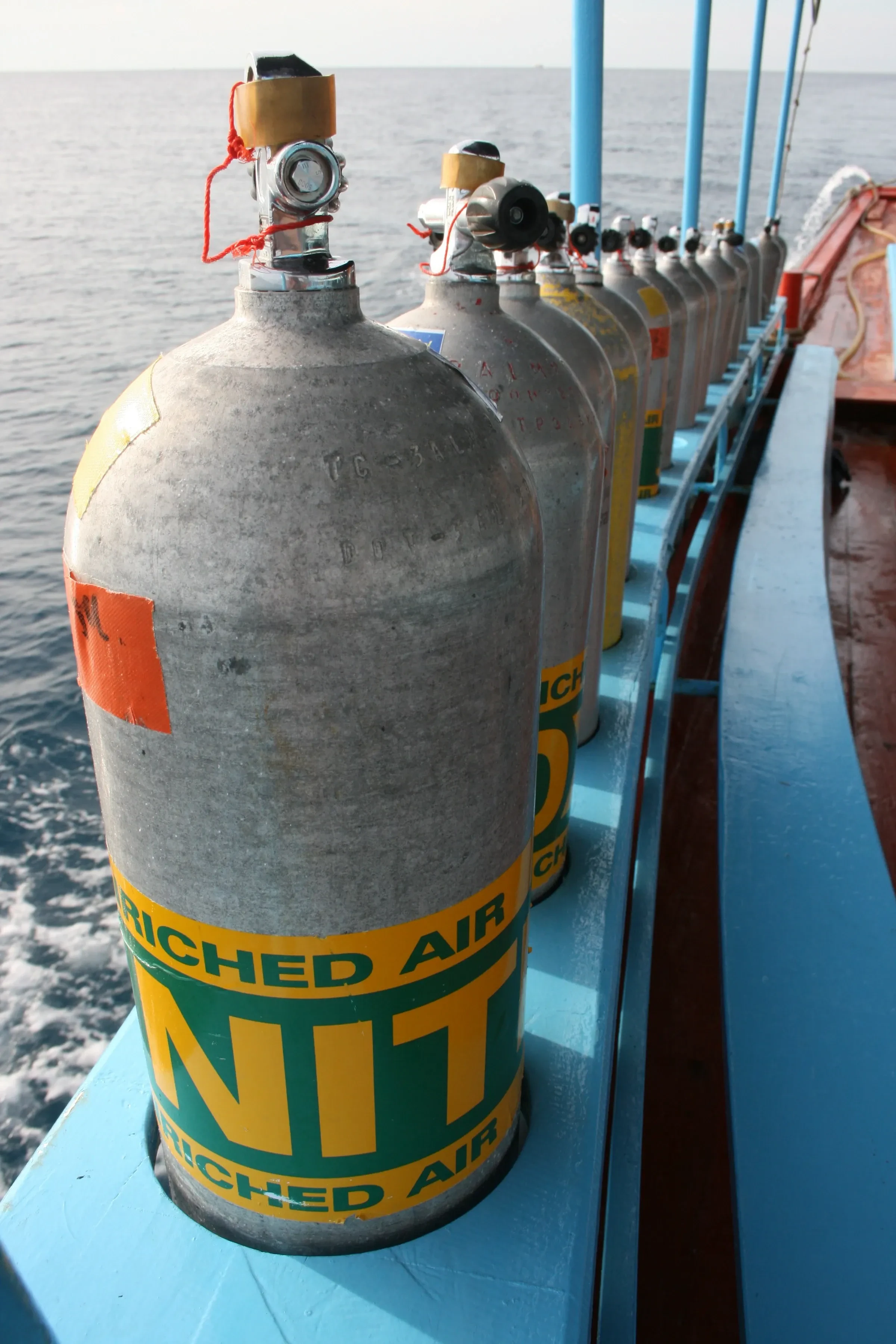 Nitrox tanks lined up along the rail of a dive boat in Koh Tao