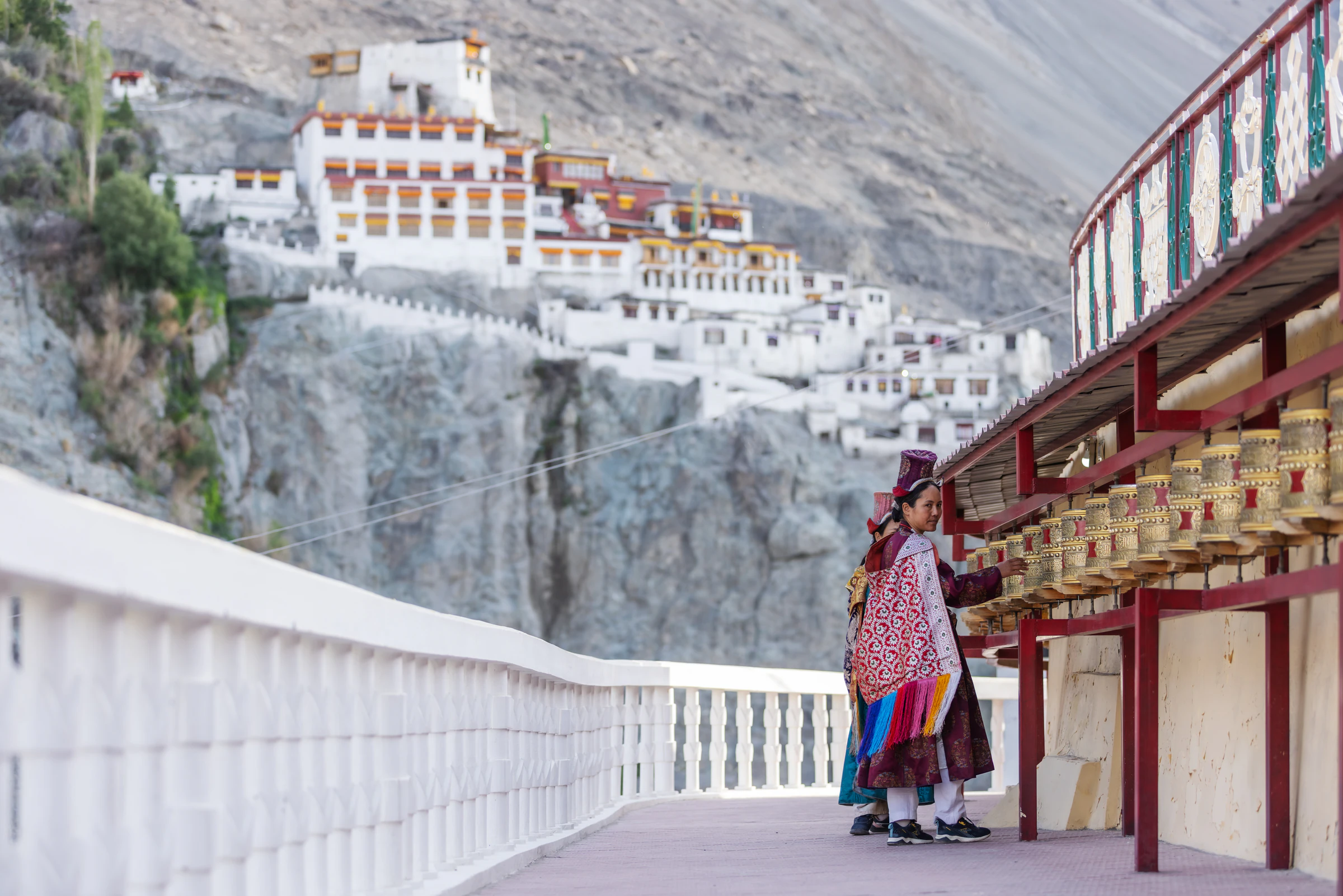 A woman walking past prayer wheels at Diskit Monastery in the Nubra Valley