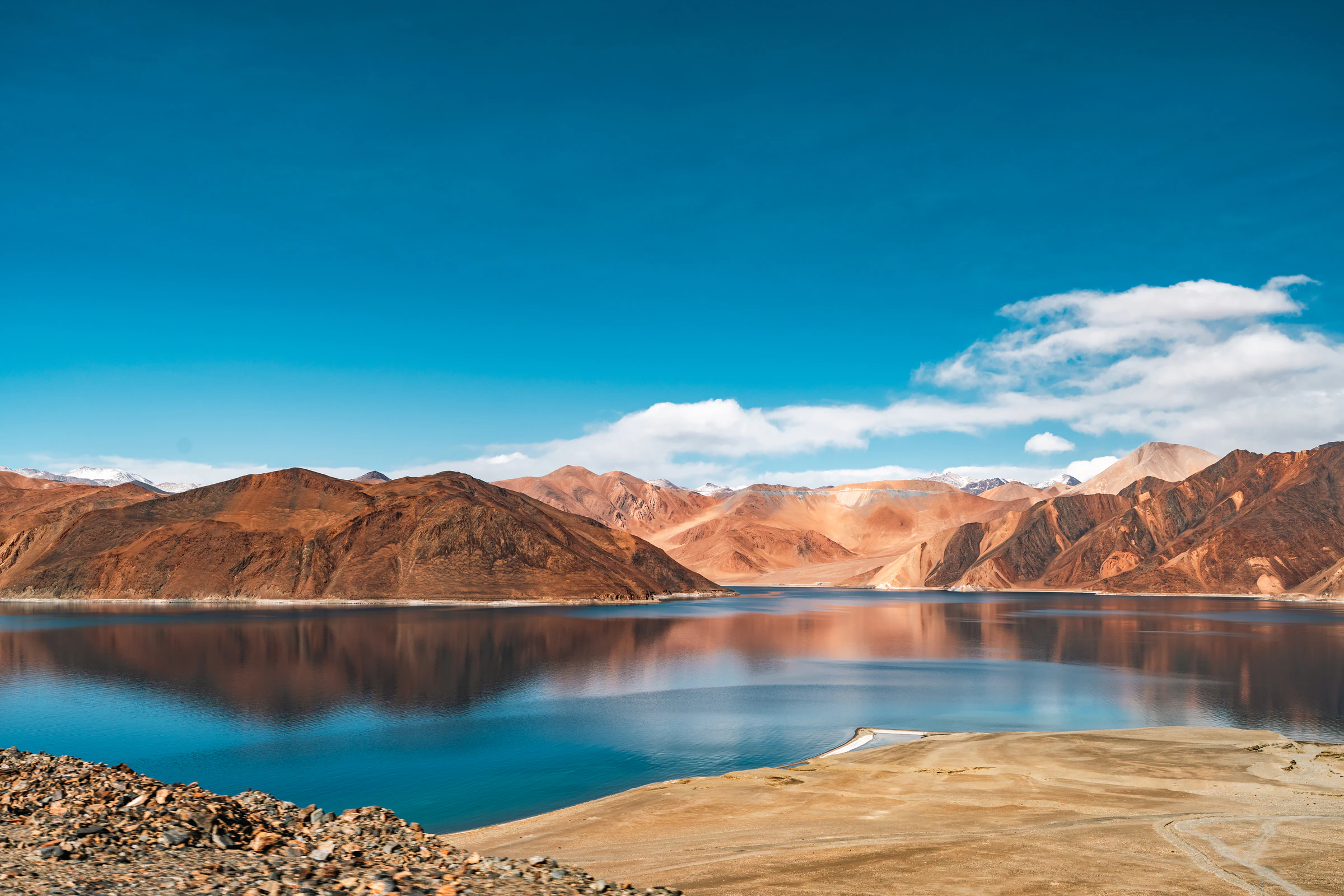 Pangong Tso under a blue sky with brown mountains around the lake