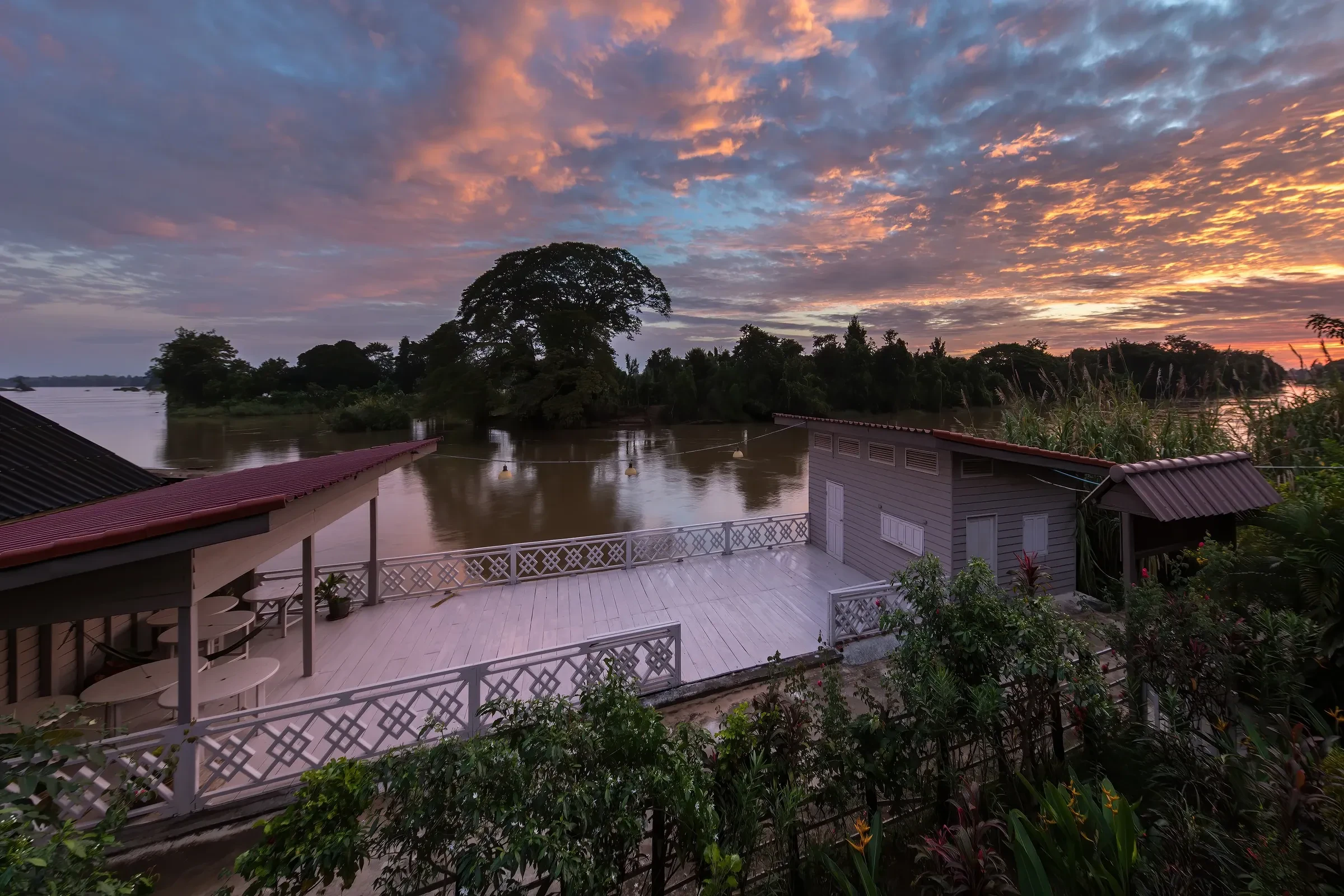Pink and orange dusk sky over the Mekong from a wooden terrace on Don Det