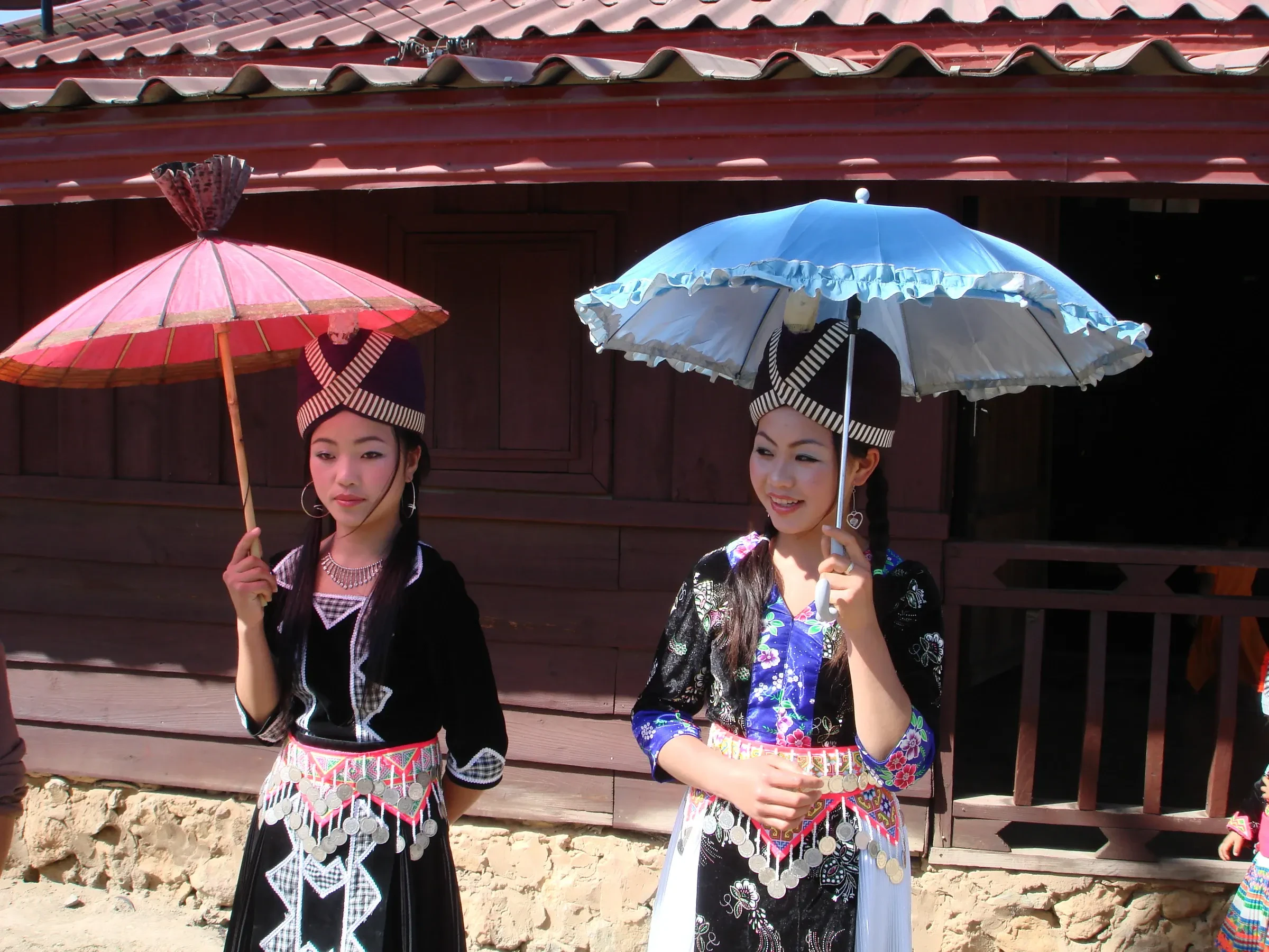 Two girls in Hmong costume with parasols at a New Year celebration in Phonsavan