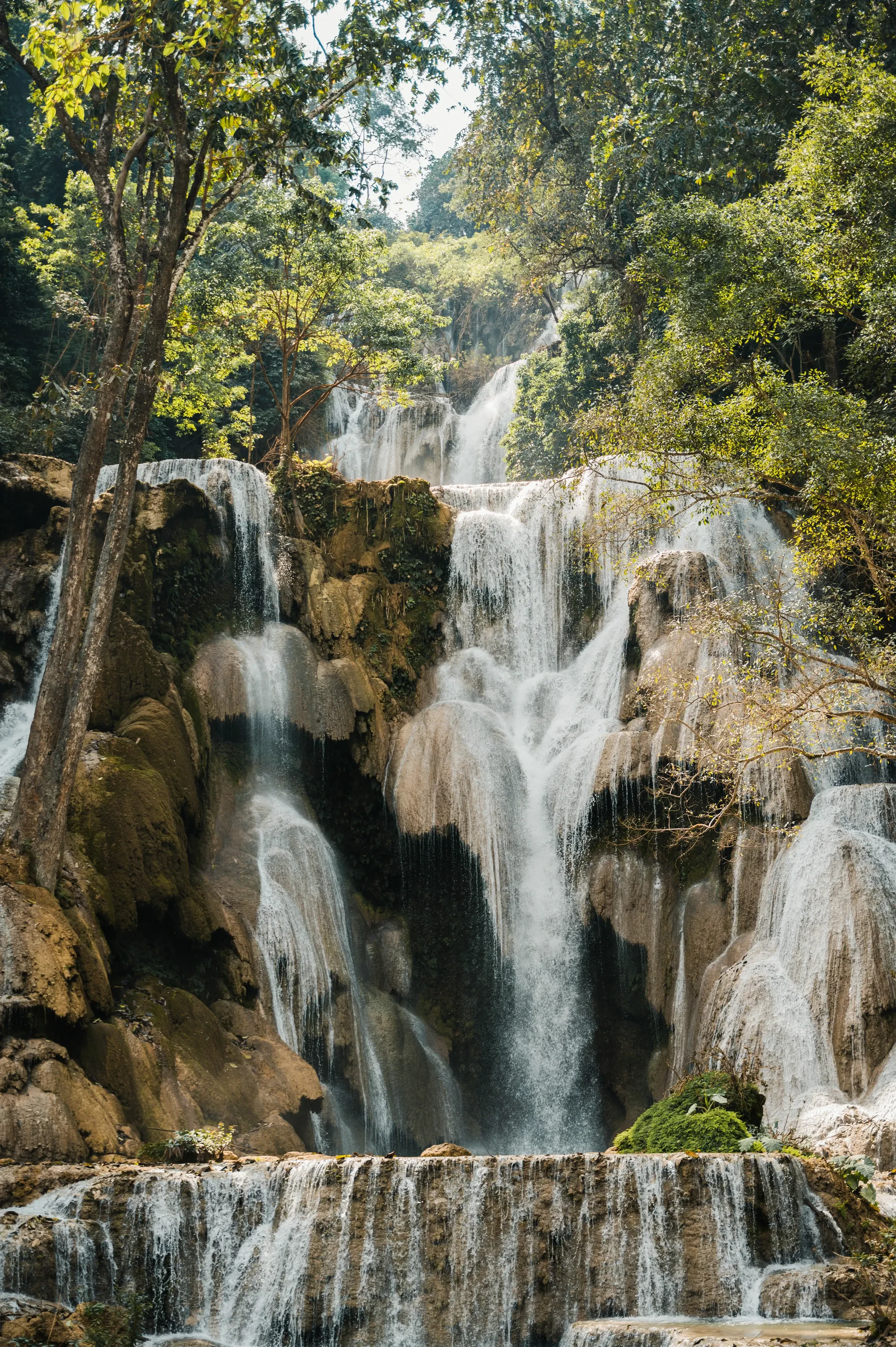 The turquoise upper tiers of Kuang Si Falls pouring through the forest near Luang Prabang