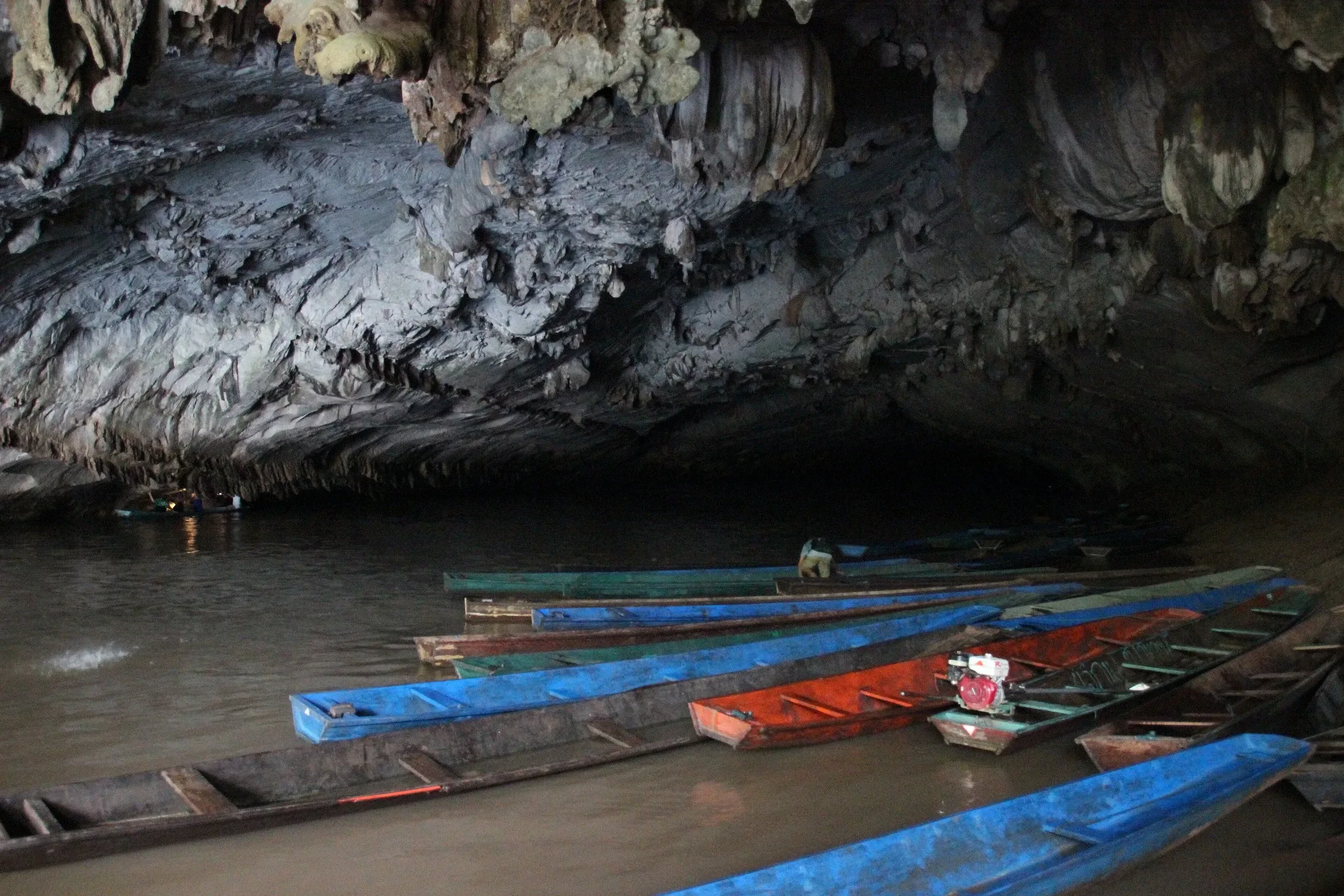 Narrow wooden boats moored inside the mouth of Kong Lor Cave