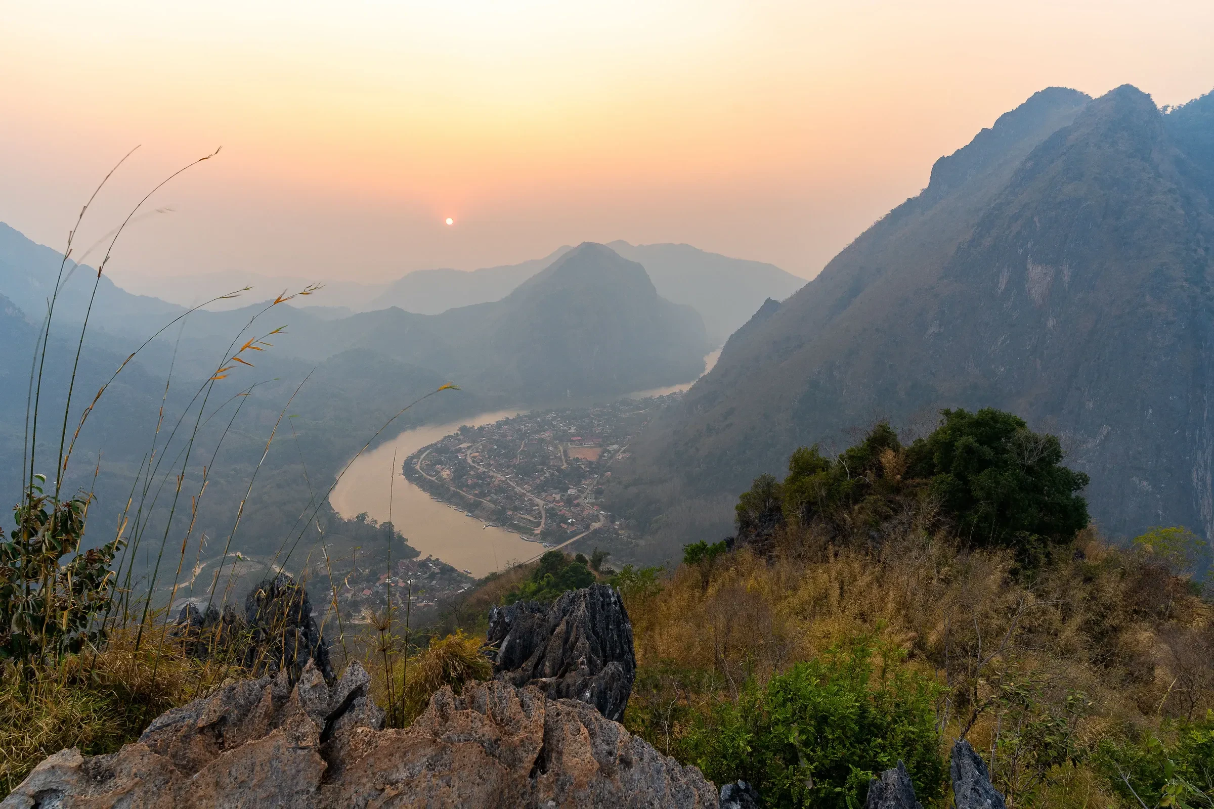 The Nam Ou river bending below the hills at Nong Khiaw at sunset, seen from a viewpoint
