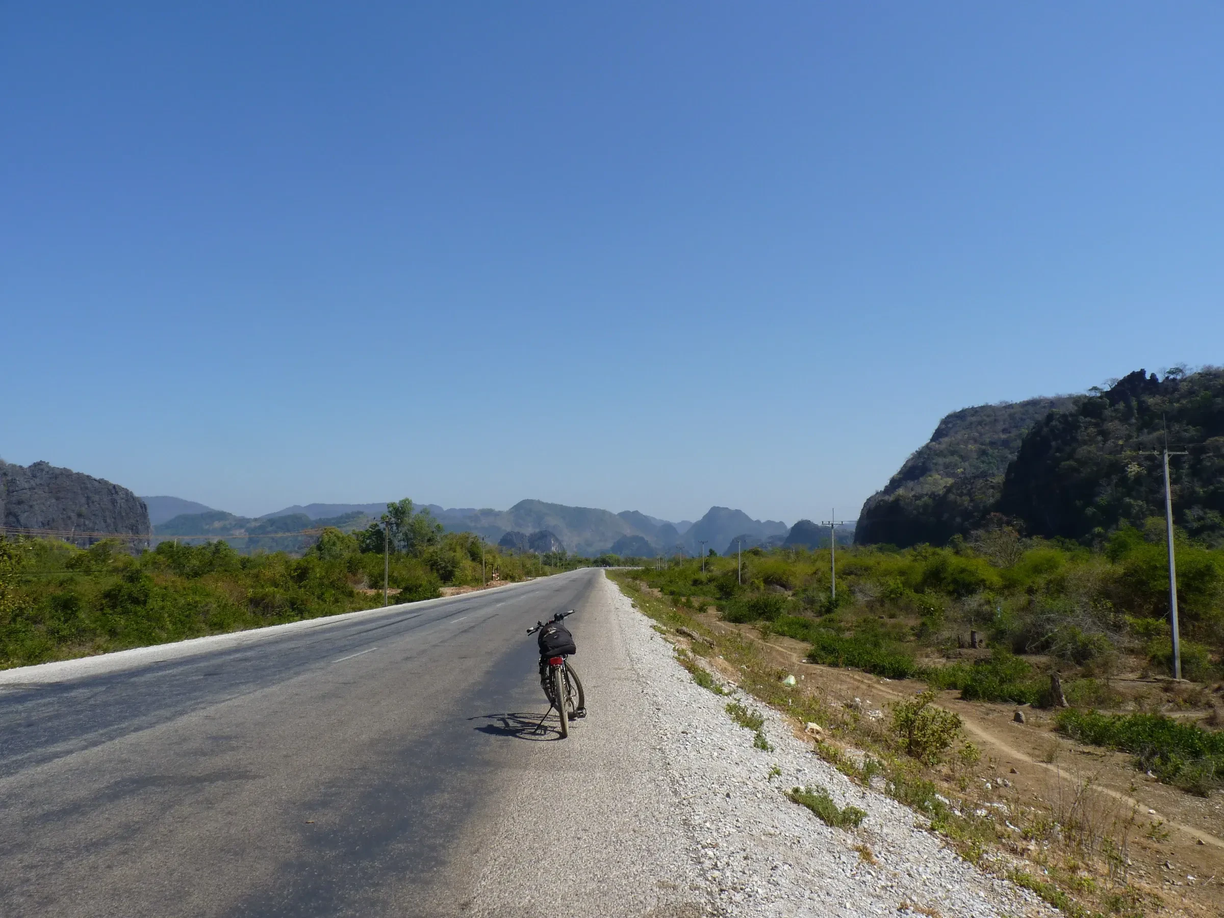 A quiet road running toward limestone hills on Route 16 outside Thakhek